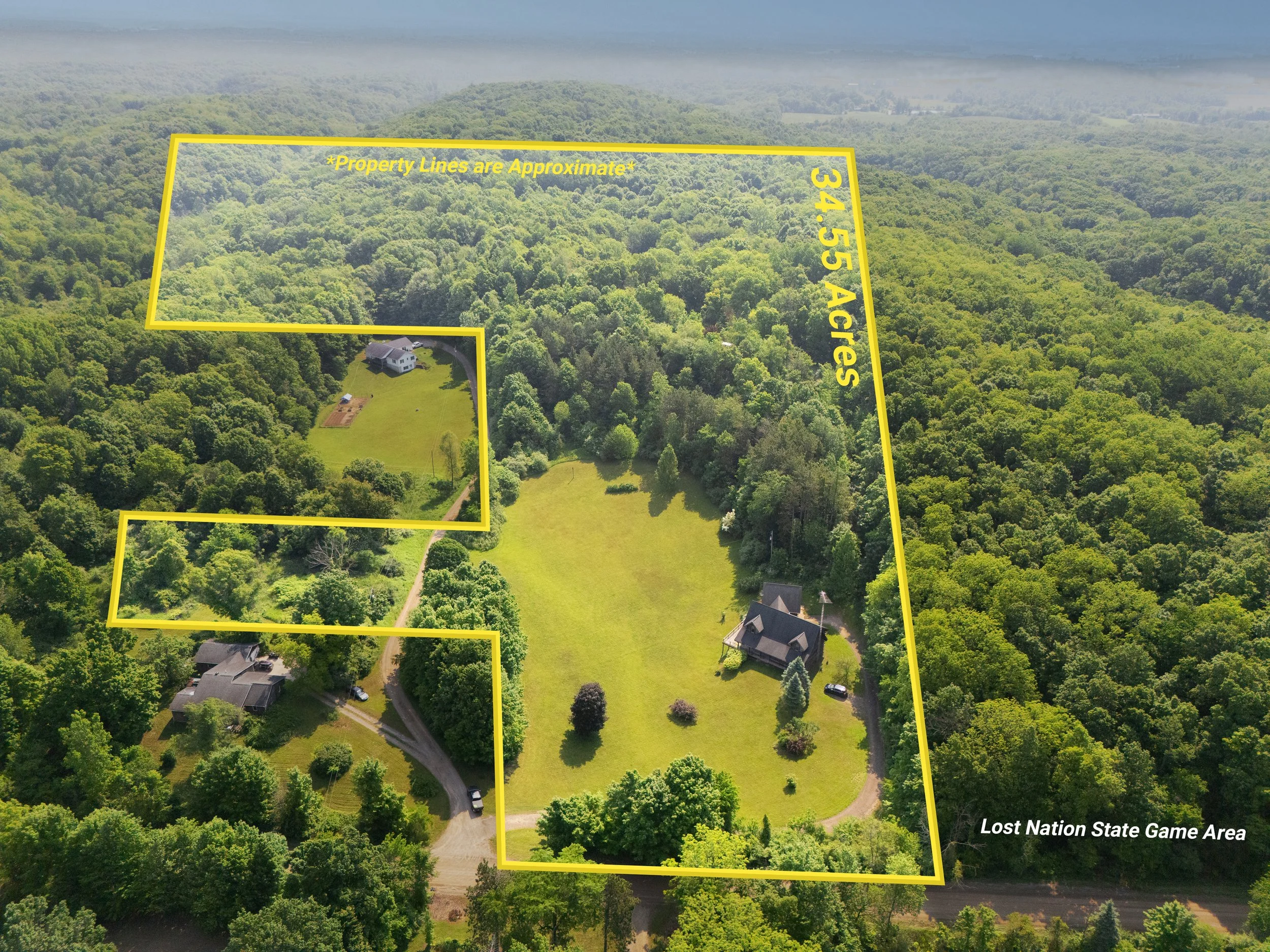Aerial view of a forested property outlined with yellow lines, showing a two-story house with a surrounding lawn, a driveway, and additional buildings nearby, with the area labeled as "Lost Nation State Game Area."
