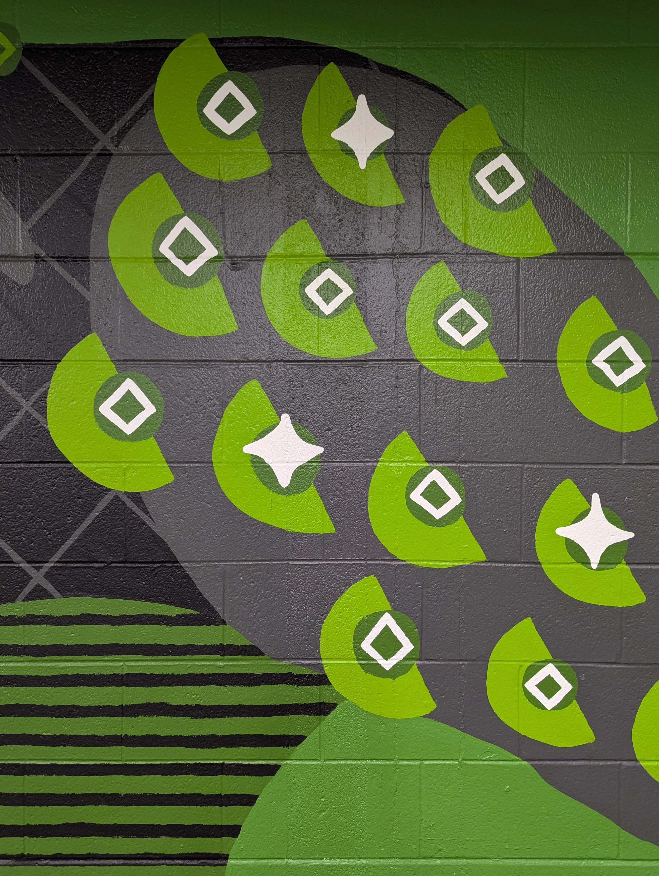 Close-up detail of half-moon, dot, and diamond patterns painted on the black panther’s leg in the elementary school animal mural.