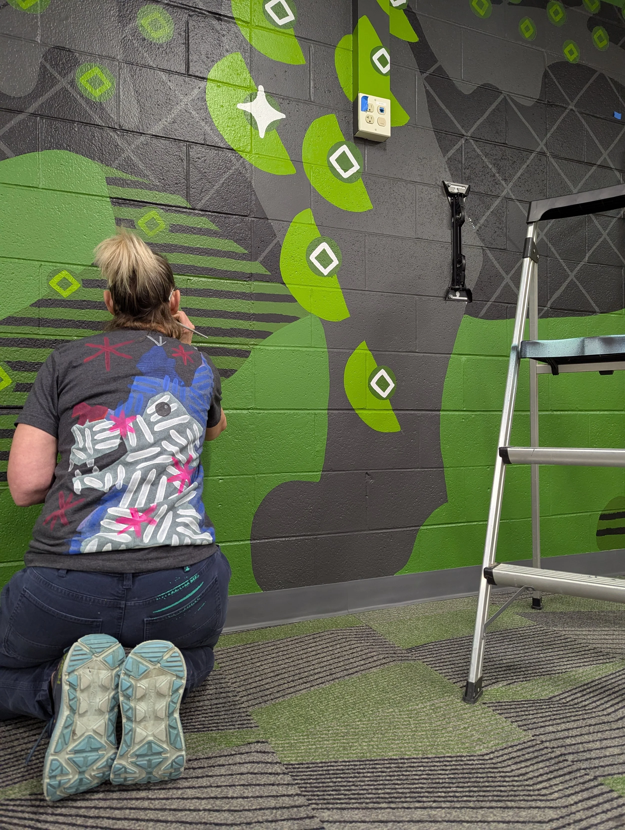 Second painter working on detailed leg stripes of the black panther elementary school mural.
