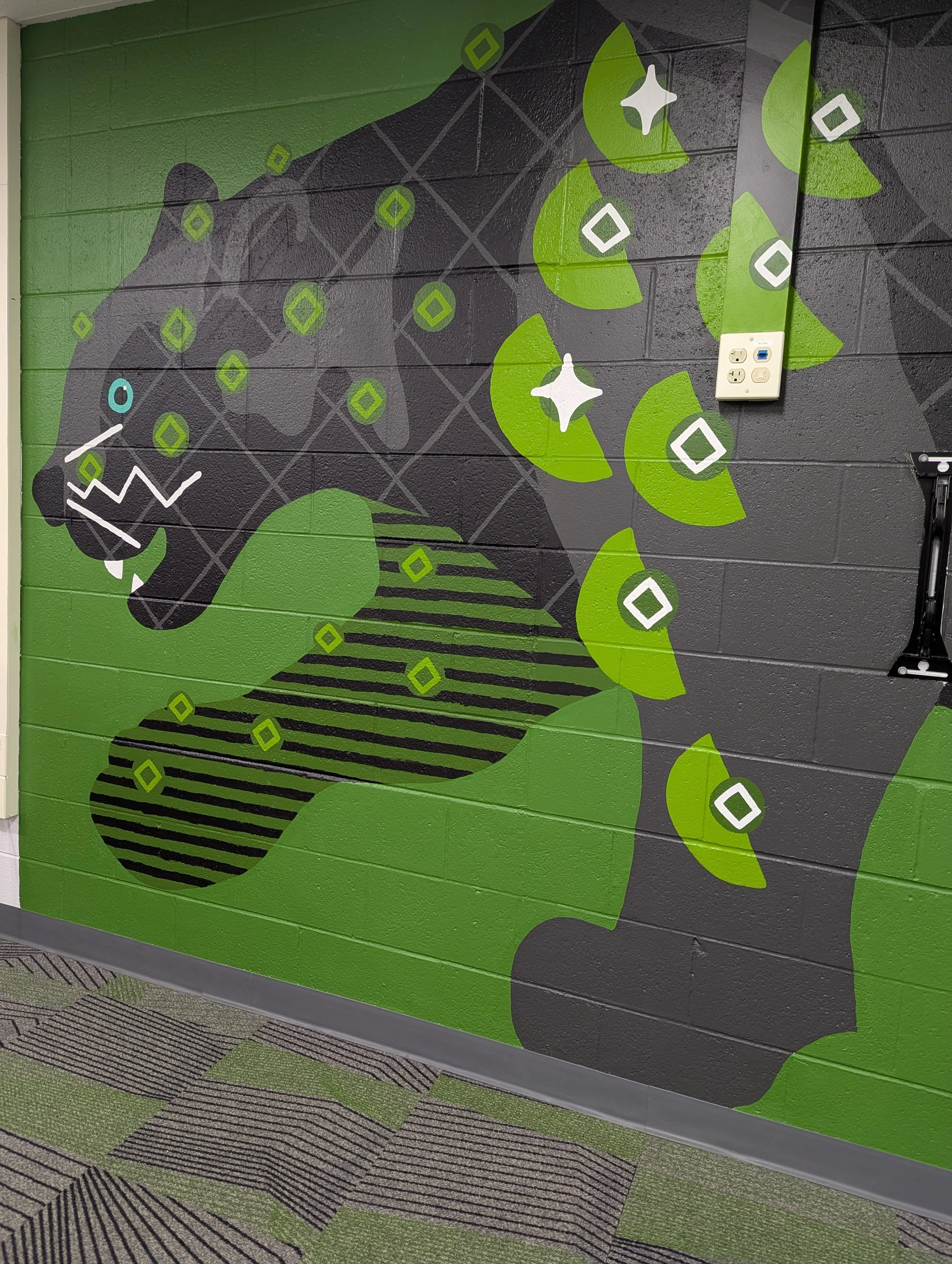 Angled crop showing front half of black panther’s head and two front legs with geometric patterns on the animal mural.