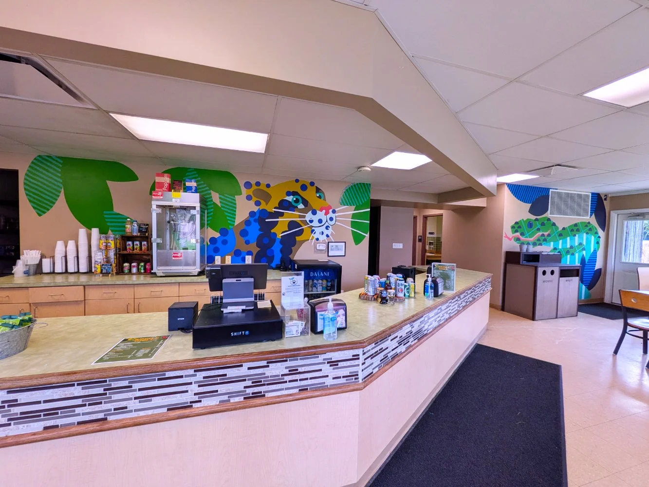 Clouded Leopard and Sumatran Pit Viper murals in the Jungle Grill Building at the Racine Zoo, showing a colorful jungle snake and cat with leaves. Dots, stripes and layered colorful shapes.