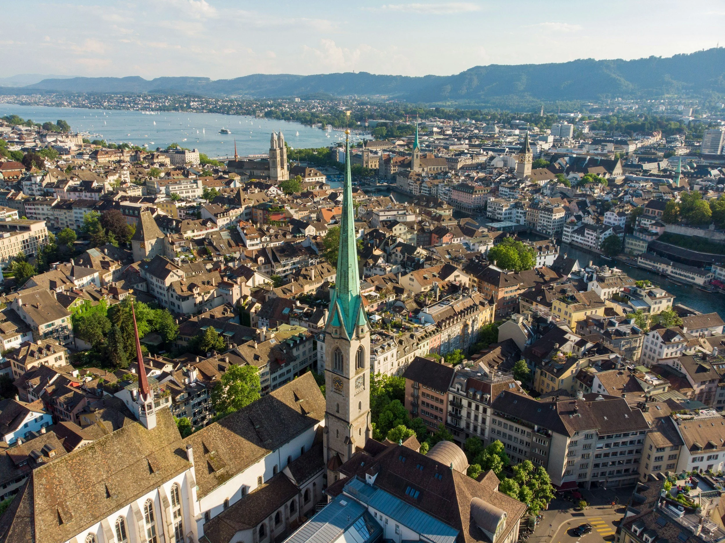 Aerial view of a city with a river, multiple buildings, and a mountain range in the background.