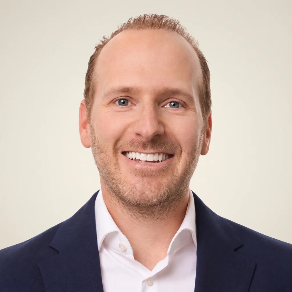 Professional headshot of a smiling man in a navy suit and white dress shirt