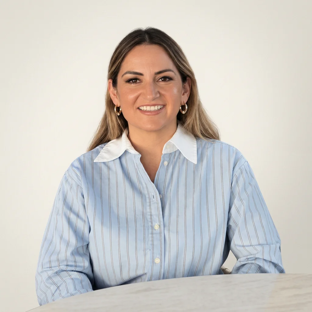 Smiling woman in a blue striped button-down shirt seated at a table