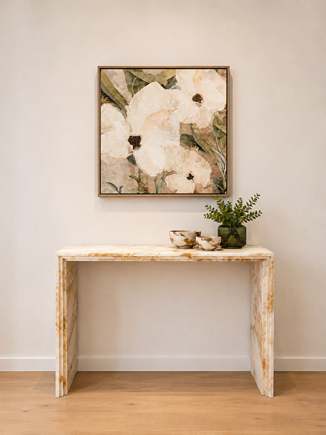 A minimalist entryway with a beige marble console table, a green vase with foliage, two decorative bowls, and a large floral artwork on a white wall.