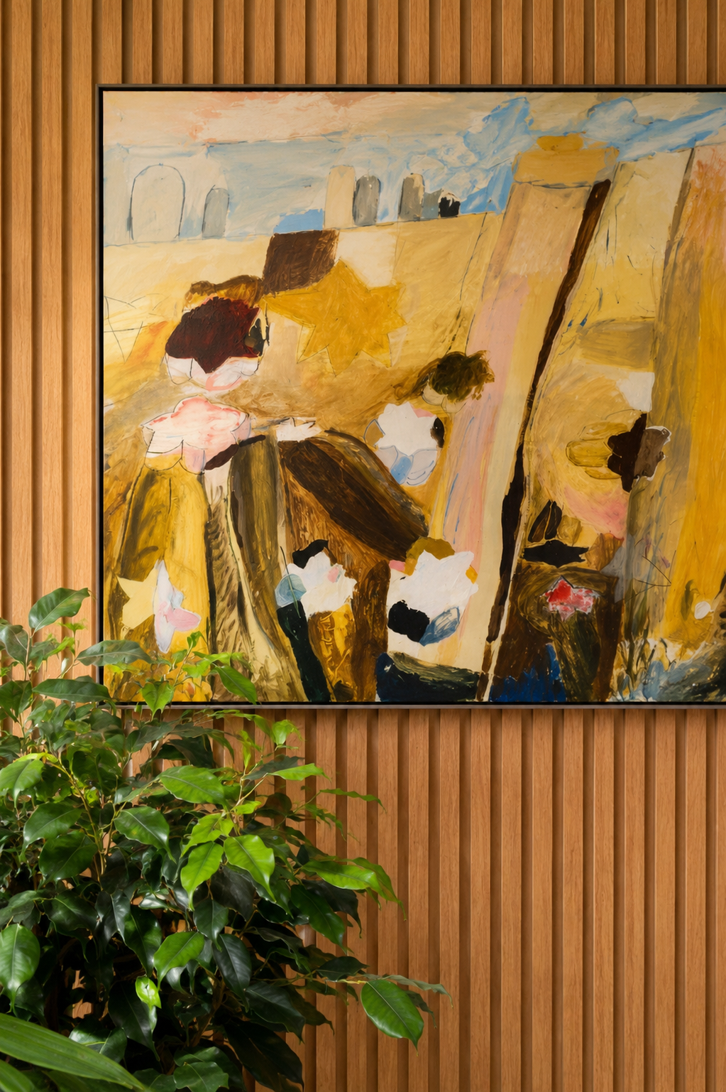 An abstract painting hanging on a wooden slat wall, depicting figures, star shapes, and various colors, with a green leafy plant in the foreground.