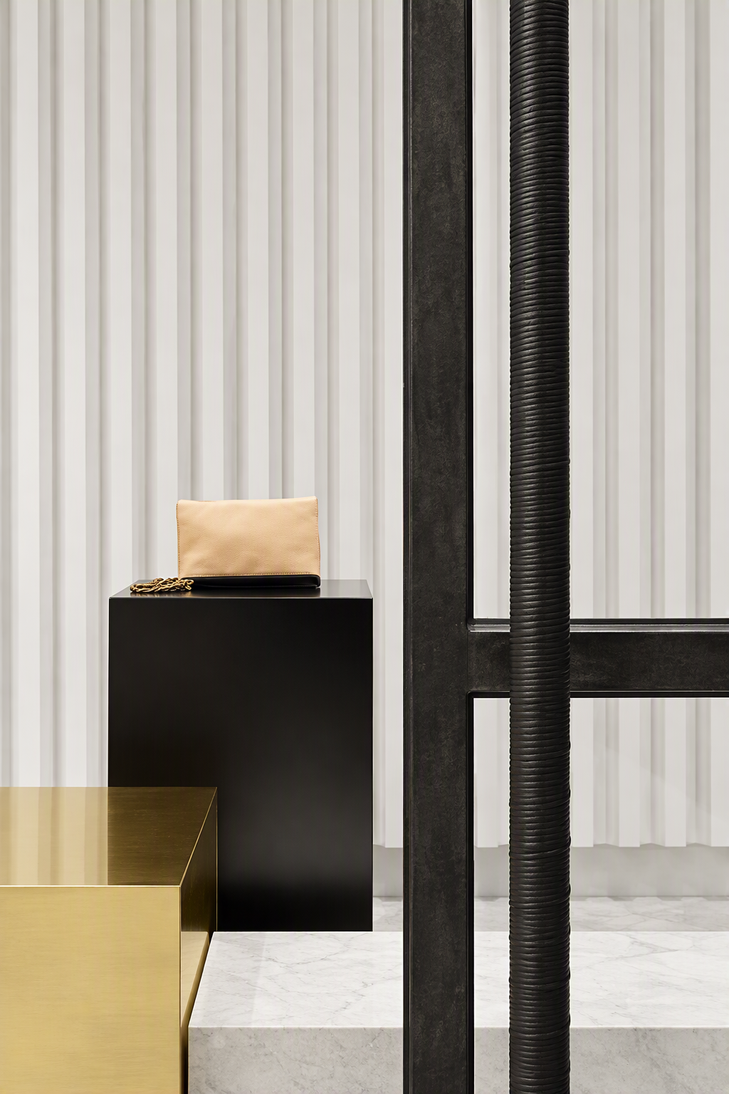 Interior space with a black table holding a beige bag and some items, a large vertical black structural pole, and white vertical paneling walls.