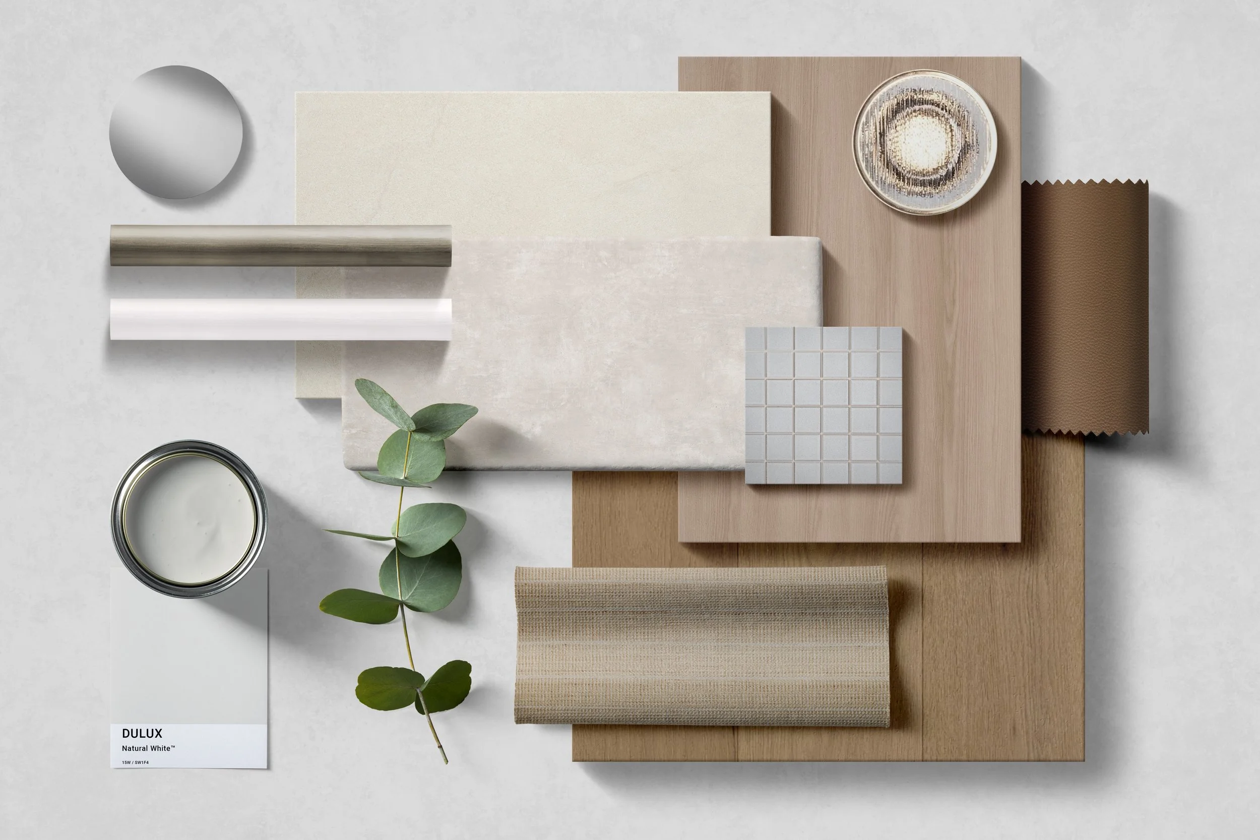 Arrangement of interior design materials including marble, wood, fabric samples, a small plant, a bowl of paint, and various color and texture swatches on a white surface.