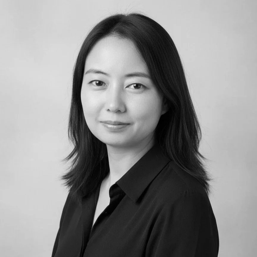 Black and white portrait of a woman with shoulder-length dark hair, wearing a collared shirt, looking at camera with a slight smile.