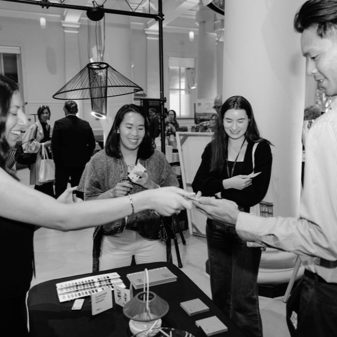 People at a booth exchanging business cards at an indoor event or conference.