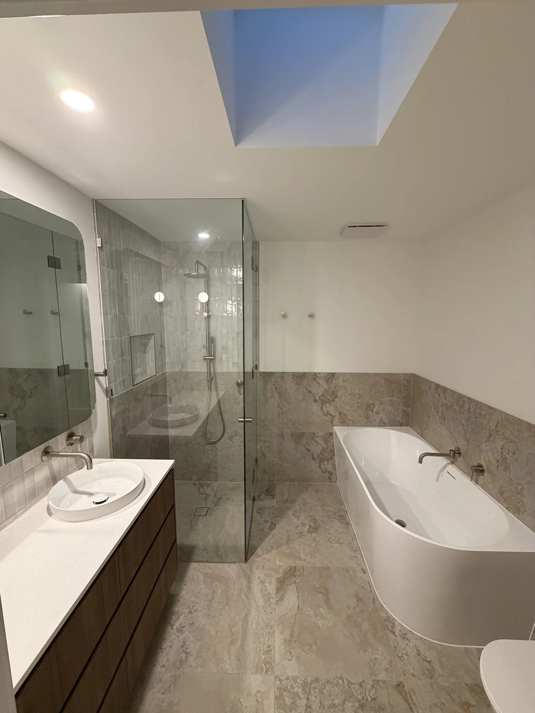Finished bathroom renovation with freestanding bath, skylight and frameless shower