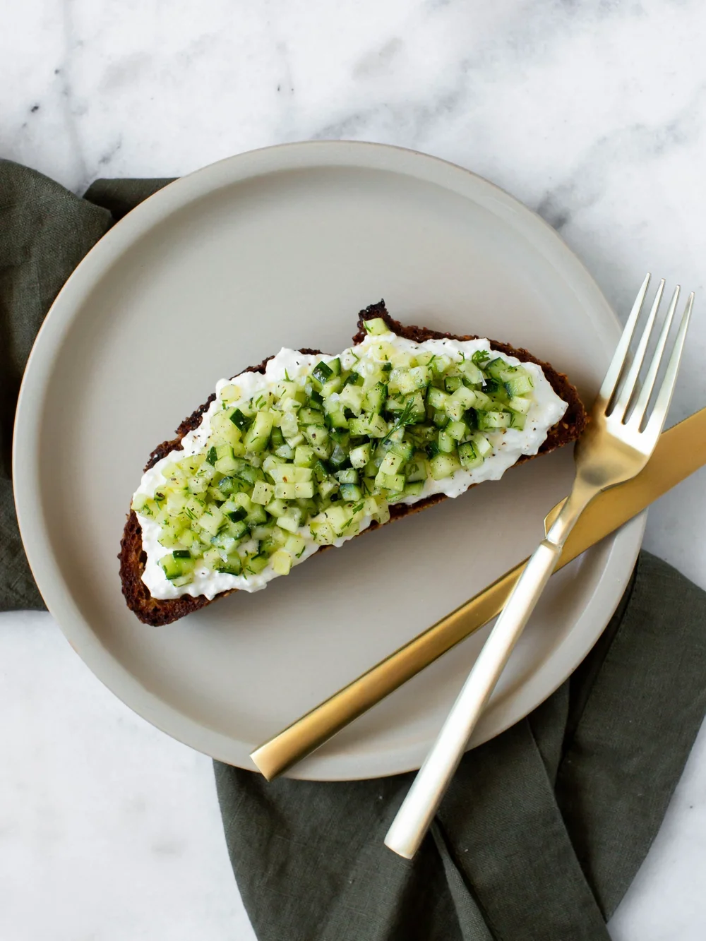 Cottage cheese in a small bowl with sliced cucumber and fresh dill as a high protein low calorie snack