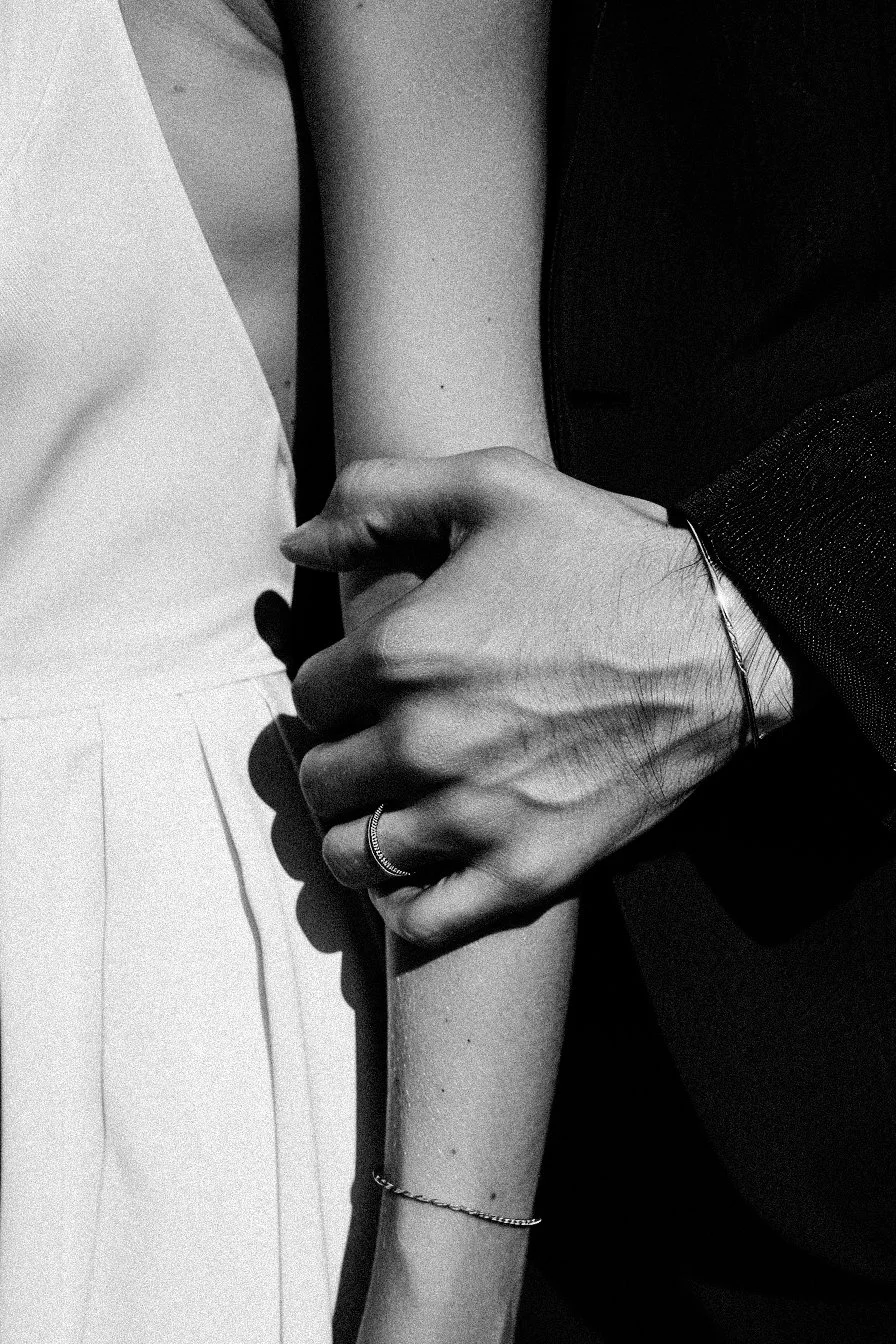 Close-up of two people holding hands, one person's hand on top of the other's arm.