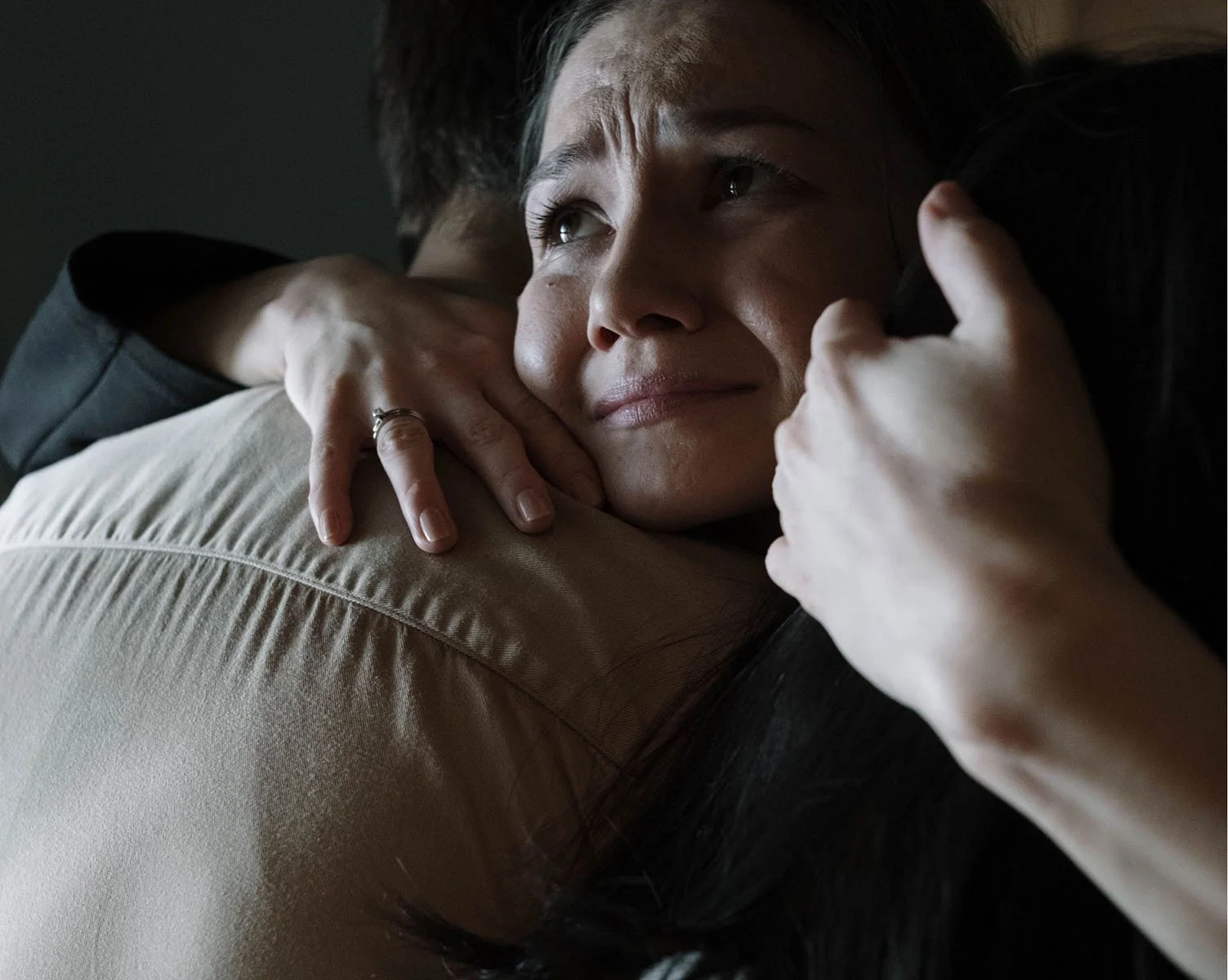 A woman comforting a person, hugging them tightly with a tender expression.