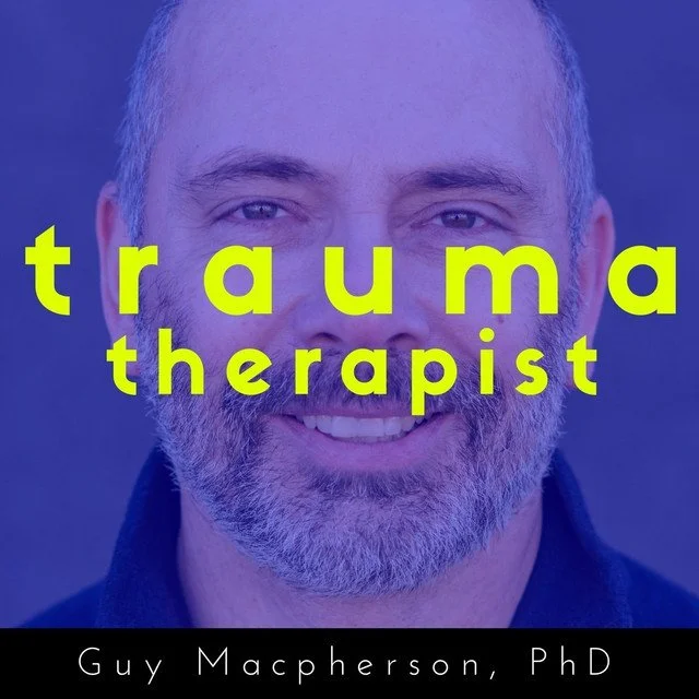 Close-up of a smiling middle-aged man with gray beard and short hair, with overlaid yellow text that says 'trauma therapist.' The background is blurry, and the bottom caption reads 'Guy Macpherson, PhD.'