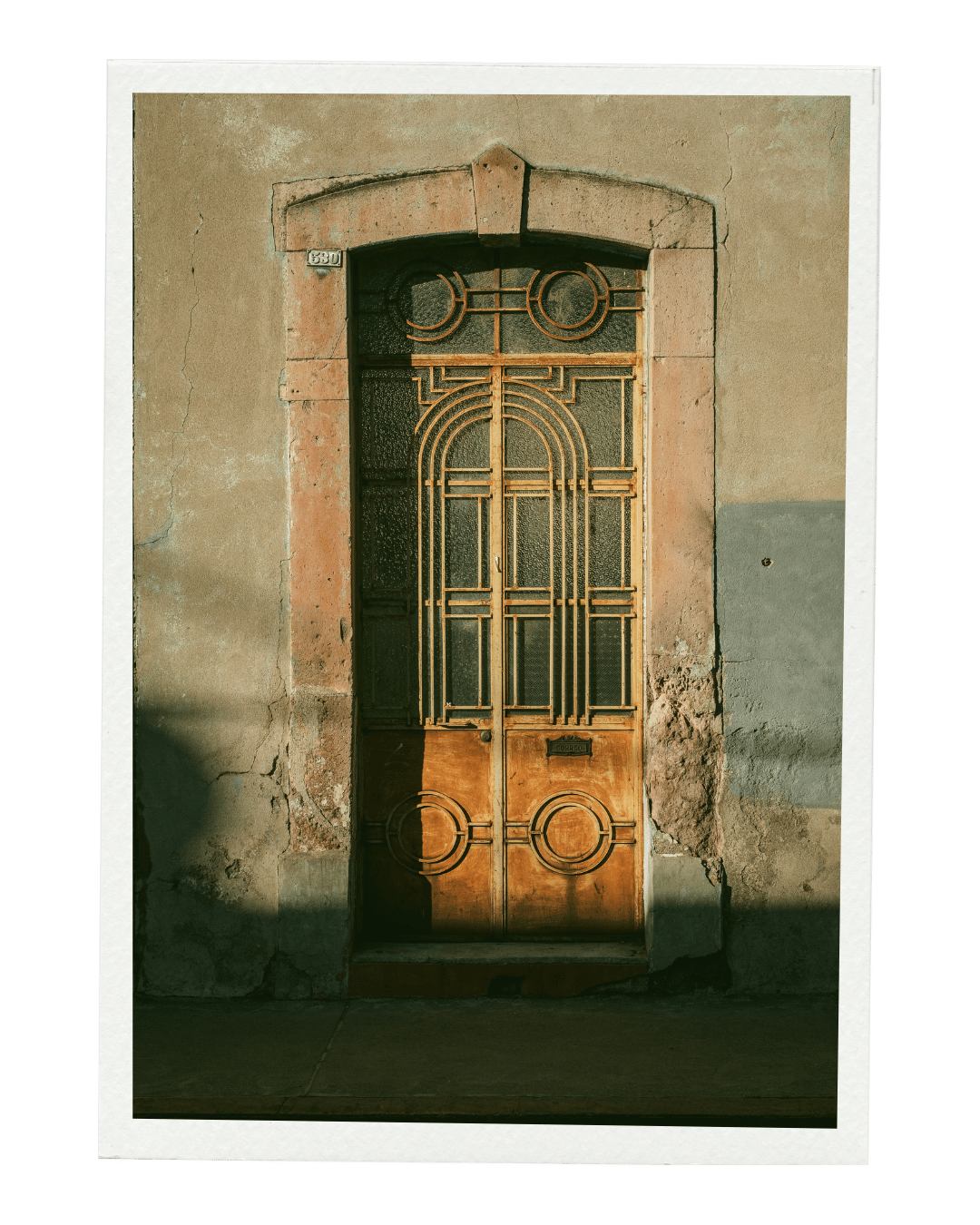 Old wooden door with decorative ironwork in a worn stone wall