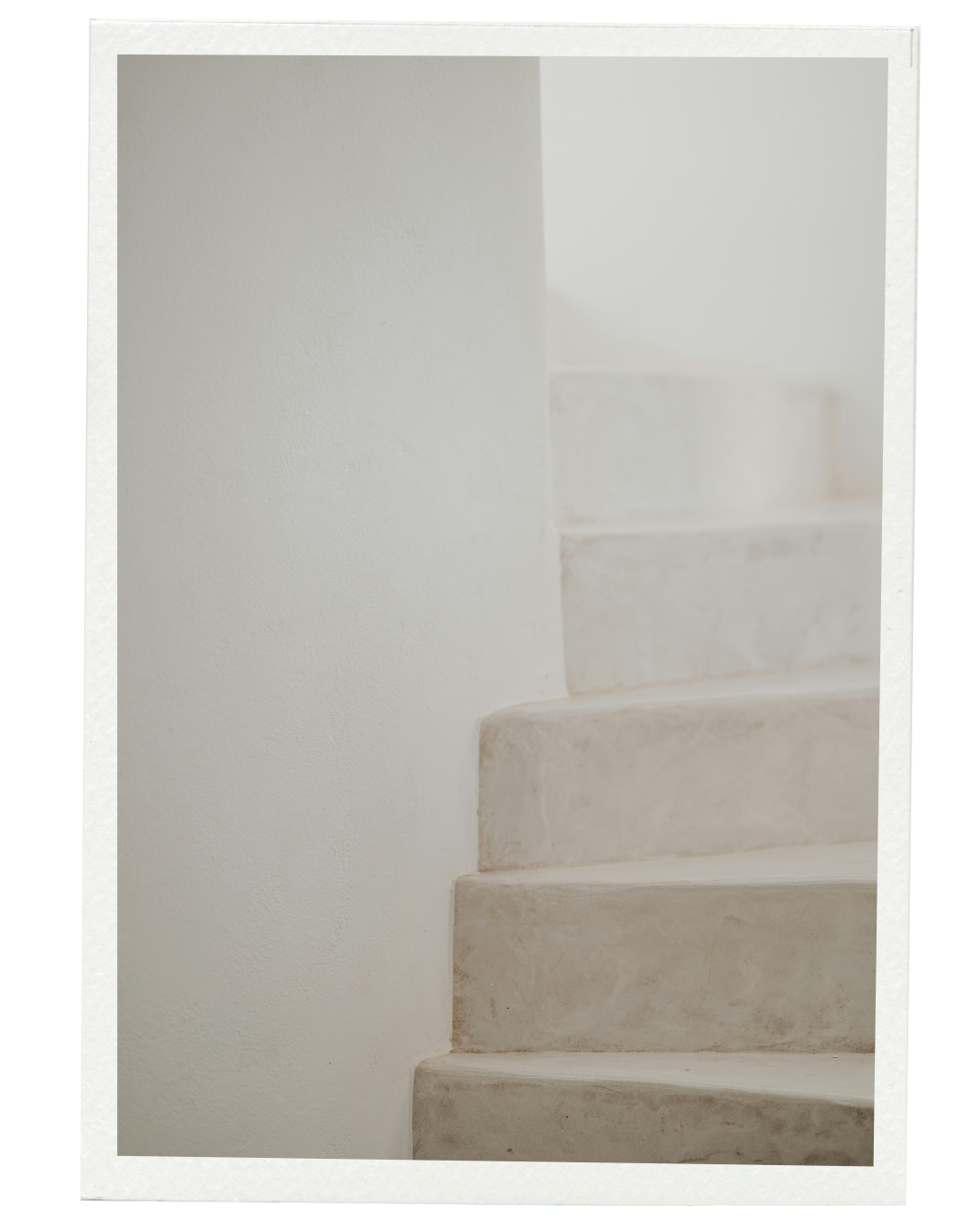 Close-up of white concrete staircase with white wall in the background.