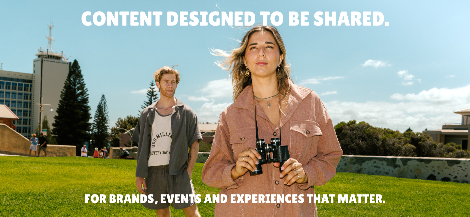 People enjoying a sunny day outdoors in a park, with two women in the foreground, one holding binoculars, and a man in the background, and text overlay saying 'Content designed to be shared. For brands, events and experiences that matter.'