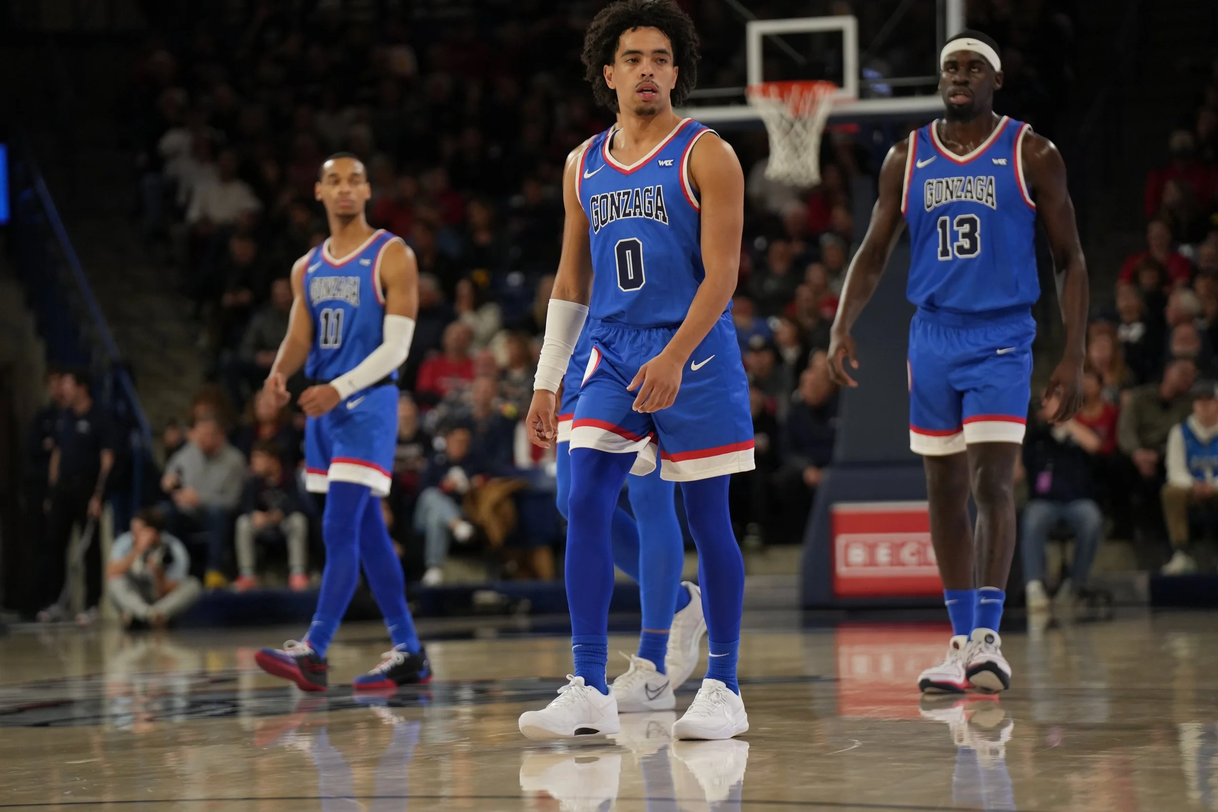 Three basketball players from Gonzaga University in blue uniforms on the court during a game.