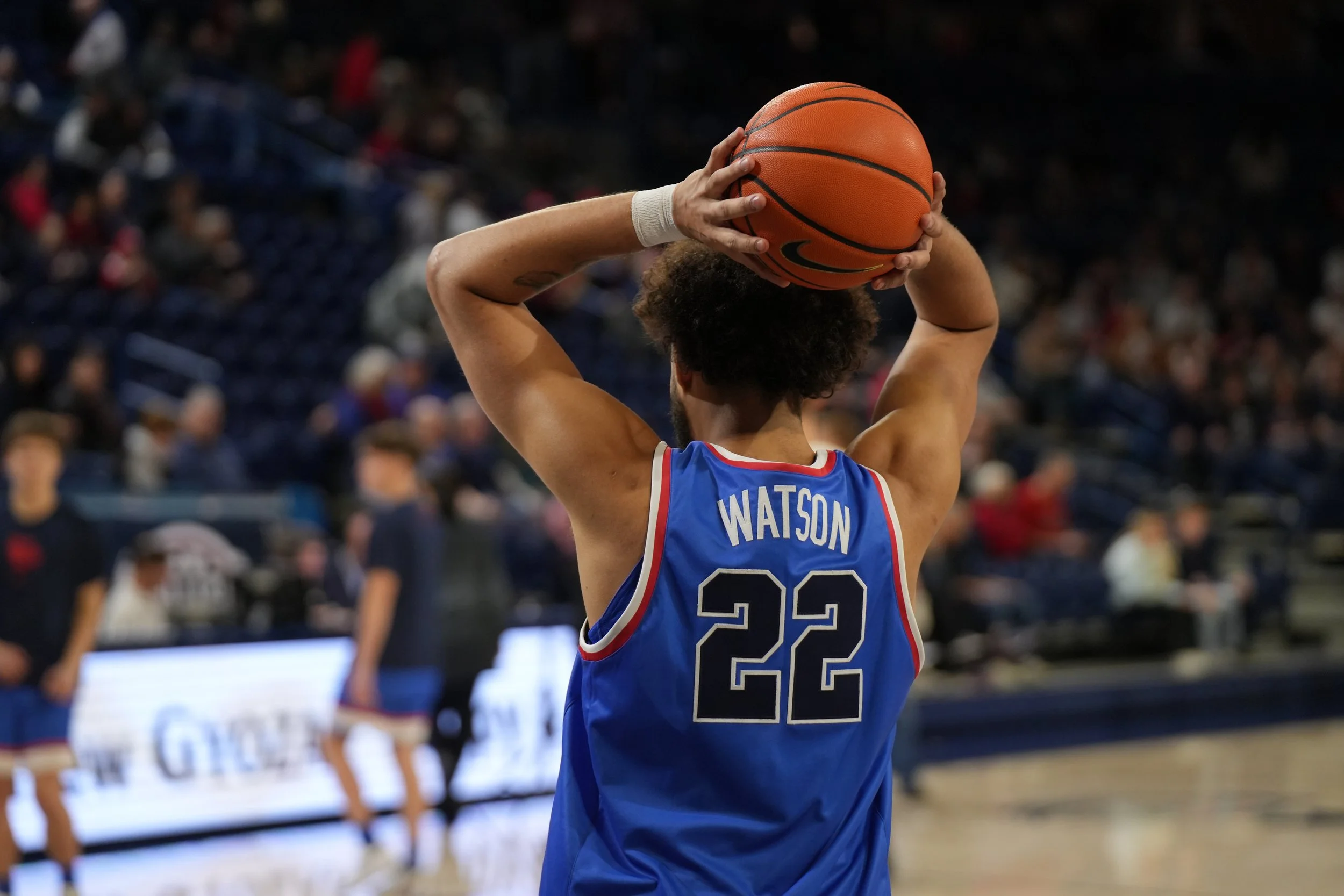 Basketball player in blue jersey number 22 holding a basketball over their head on a court.