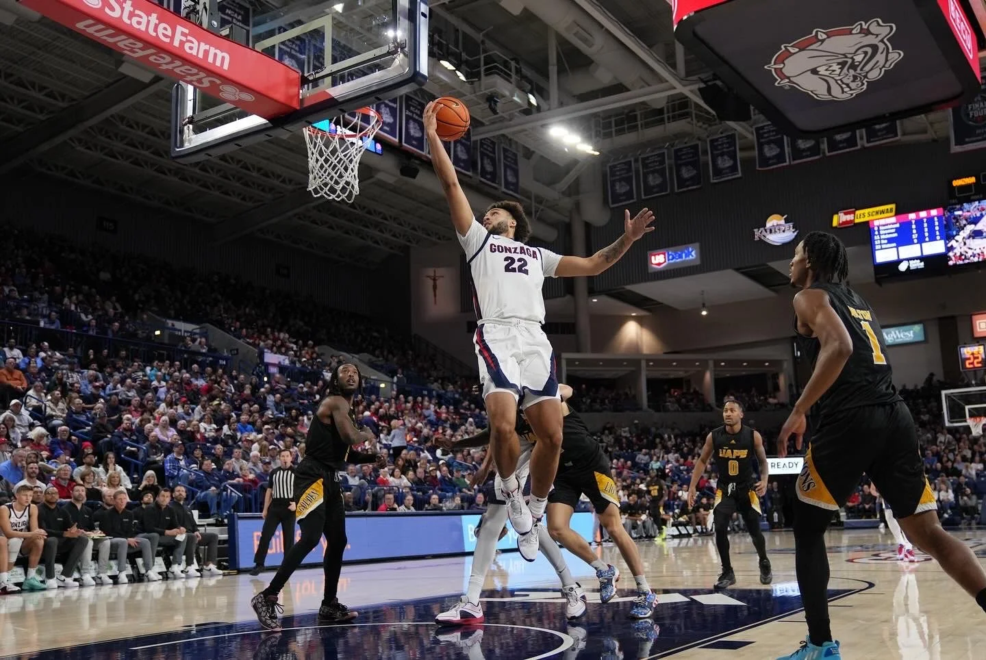 Basketball player in white jersey attempting a layup during a game in a crowded indoor stadium.