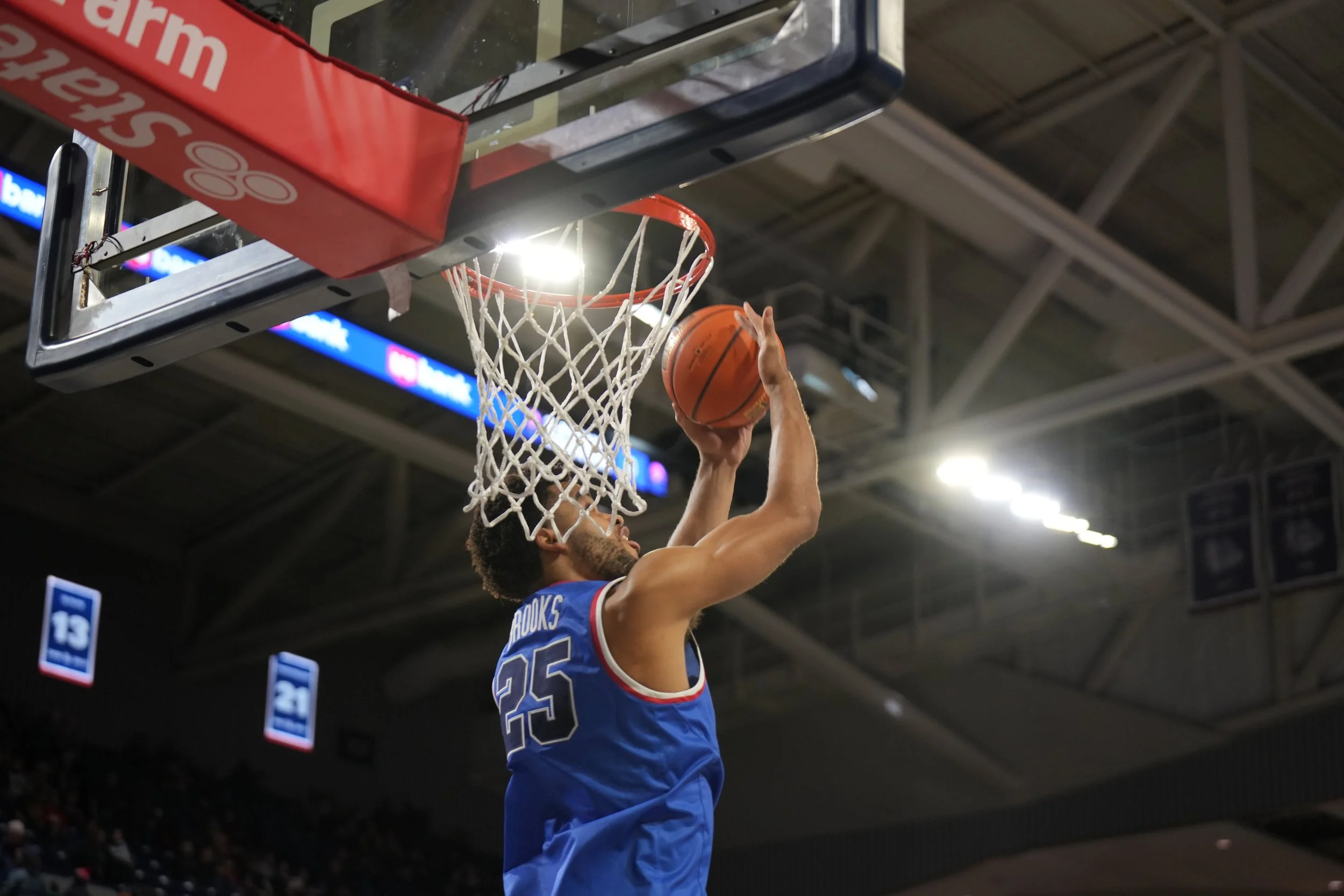 Basketball player in blue jersey dunking ball during game.
