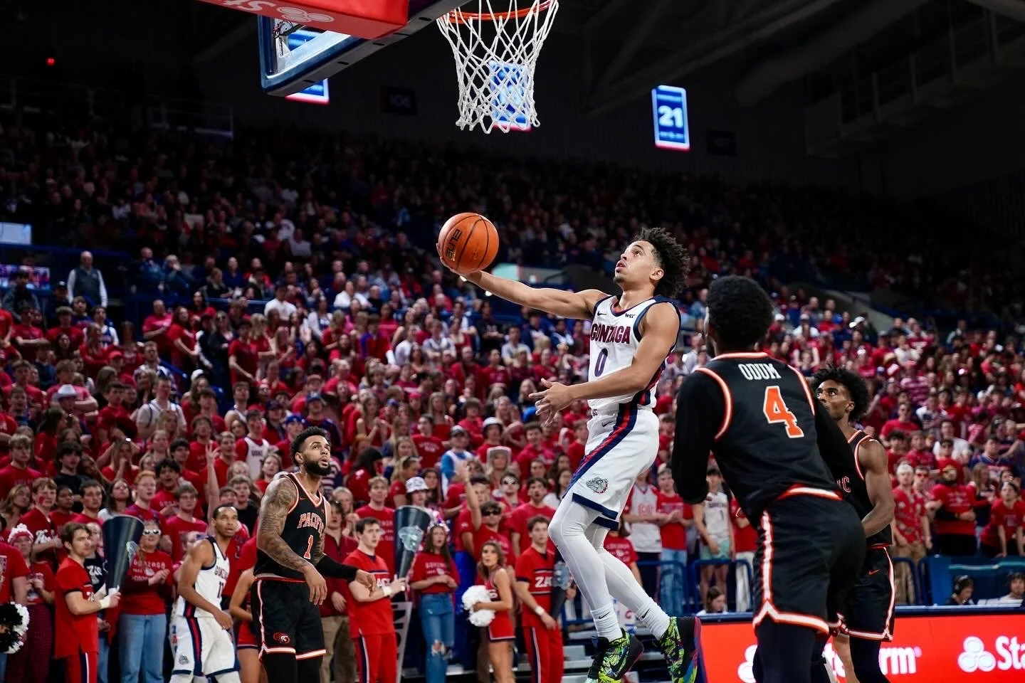 A college basketball player from Gonzaga jumping for a layup during a game against Pacific, with a crowd in the background.