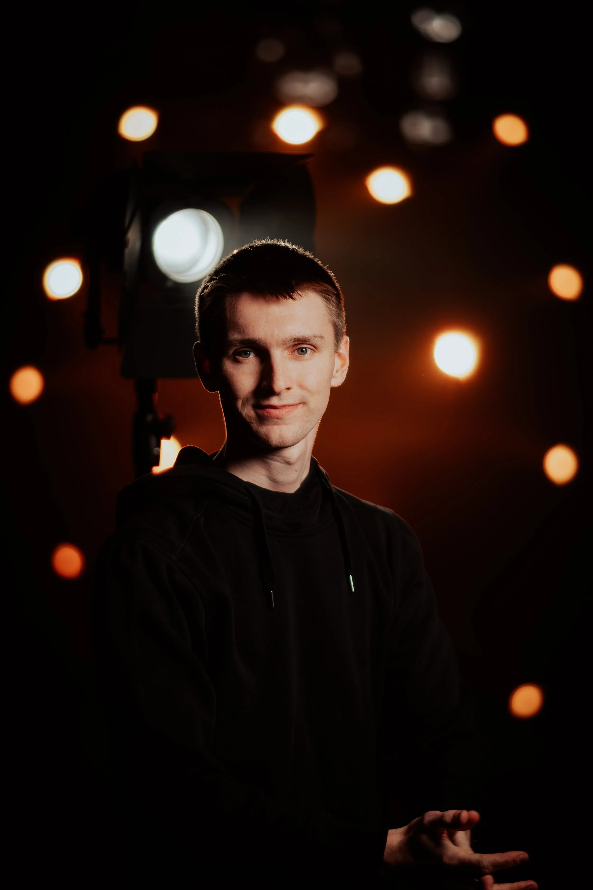 Junge Frau vor einer dunklen Kulisse mit bokeh-Lichtern, die ein Lächeln zeigt.