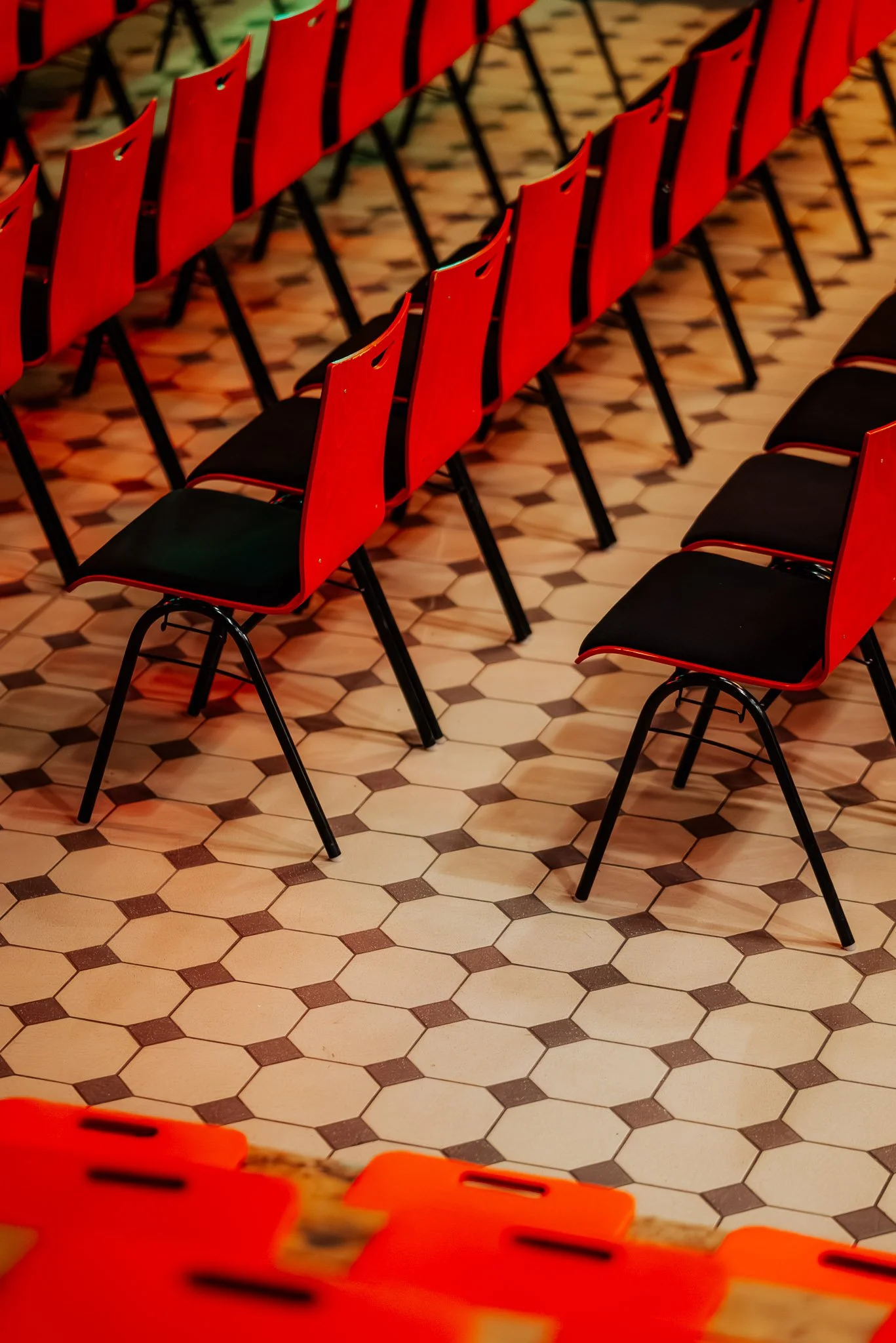 Leere rote und schwarze Stühle in einem Saal mit einem Fliesenboden.