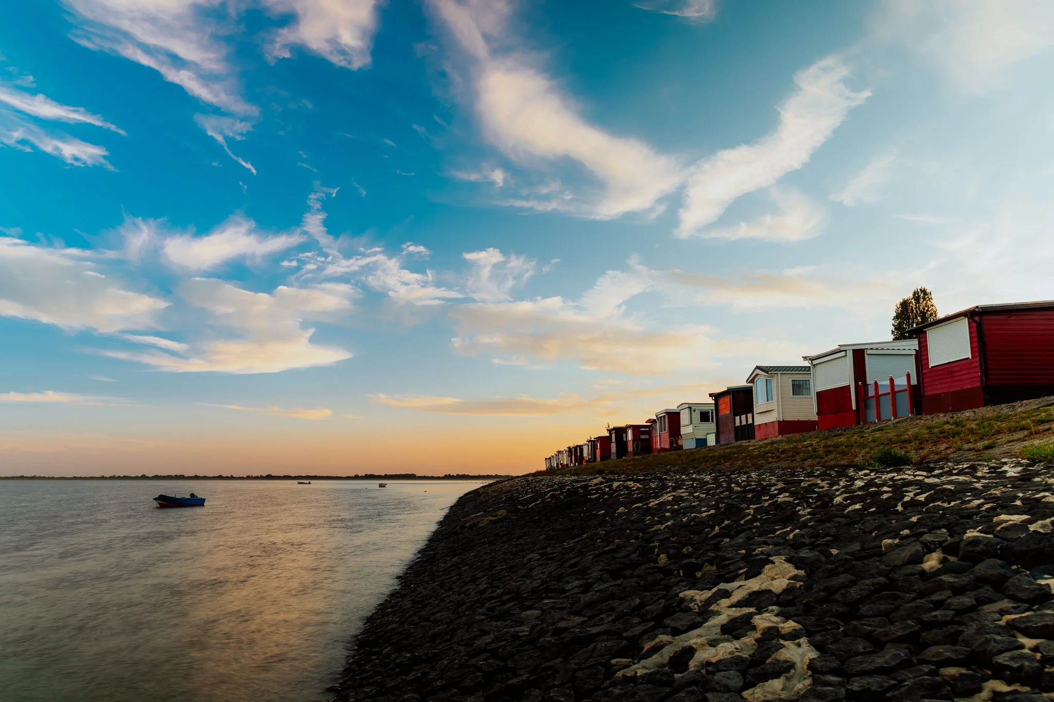 Straßen am Wasser mit bunten Häusern und einem Himmel mit Wolken bei Sonnenuntergang.