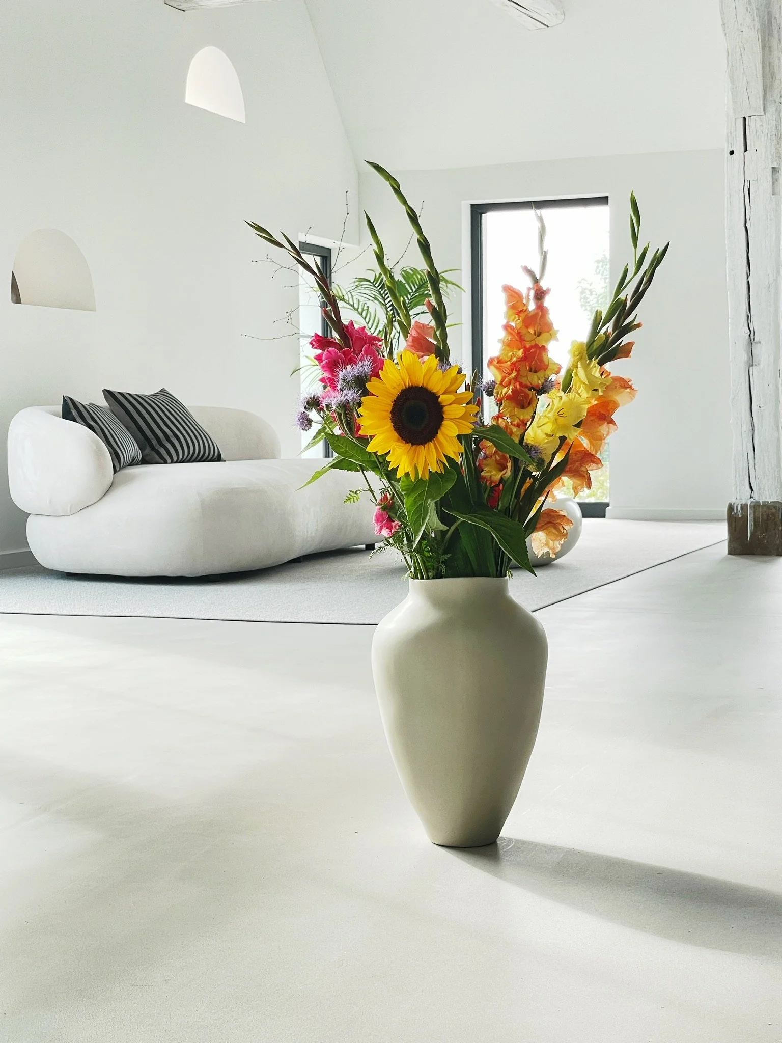 Heller Wohnbereich der Elbe04 Location bei Hamburg mit weißem Sofa und Blumenarrangement