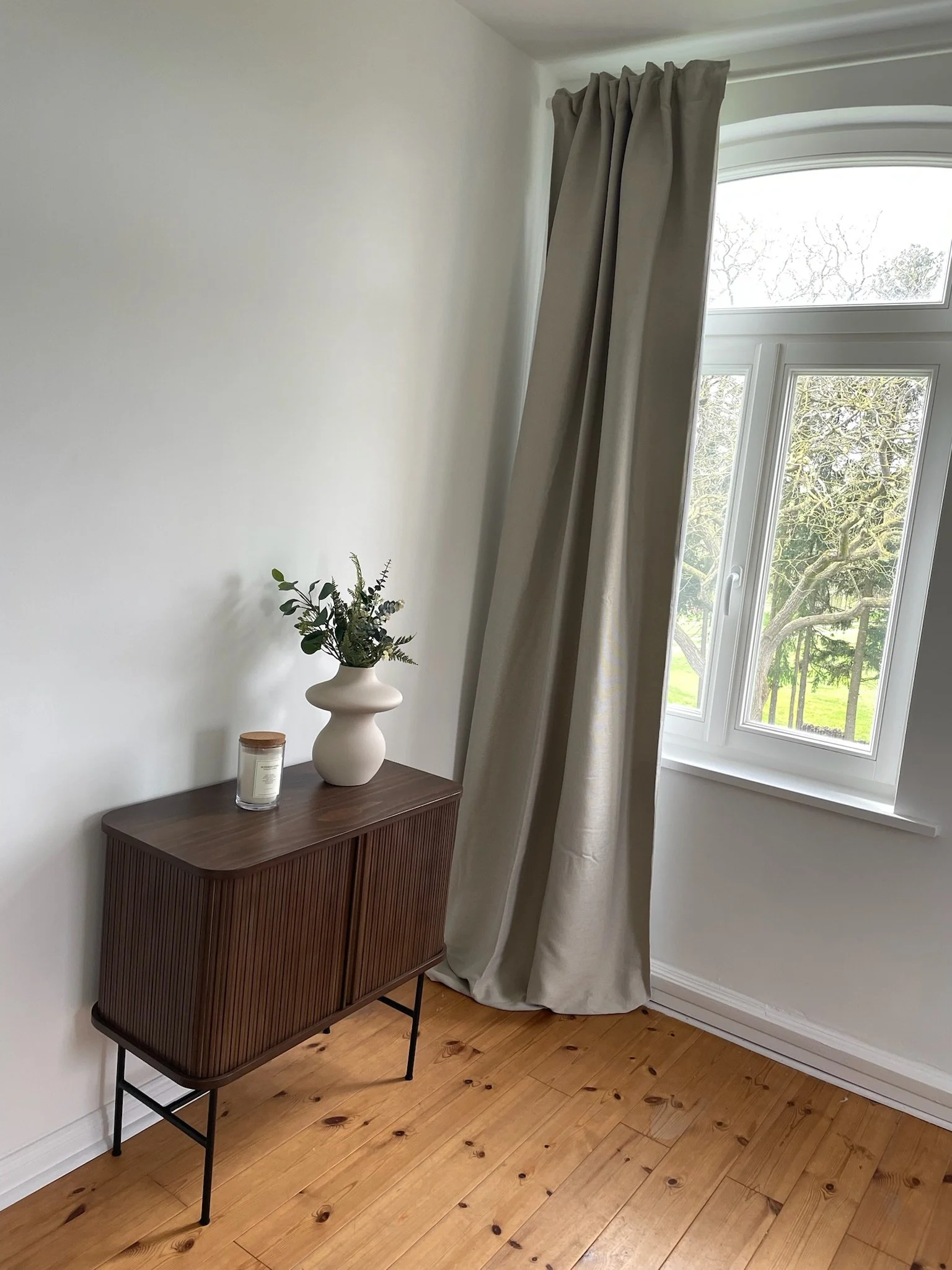 Interior-Detail mit Holzkommode und Fenster mit Blick in den Garten
