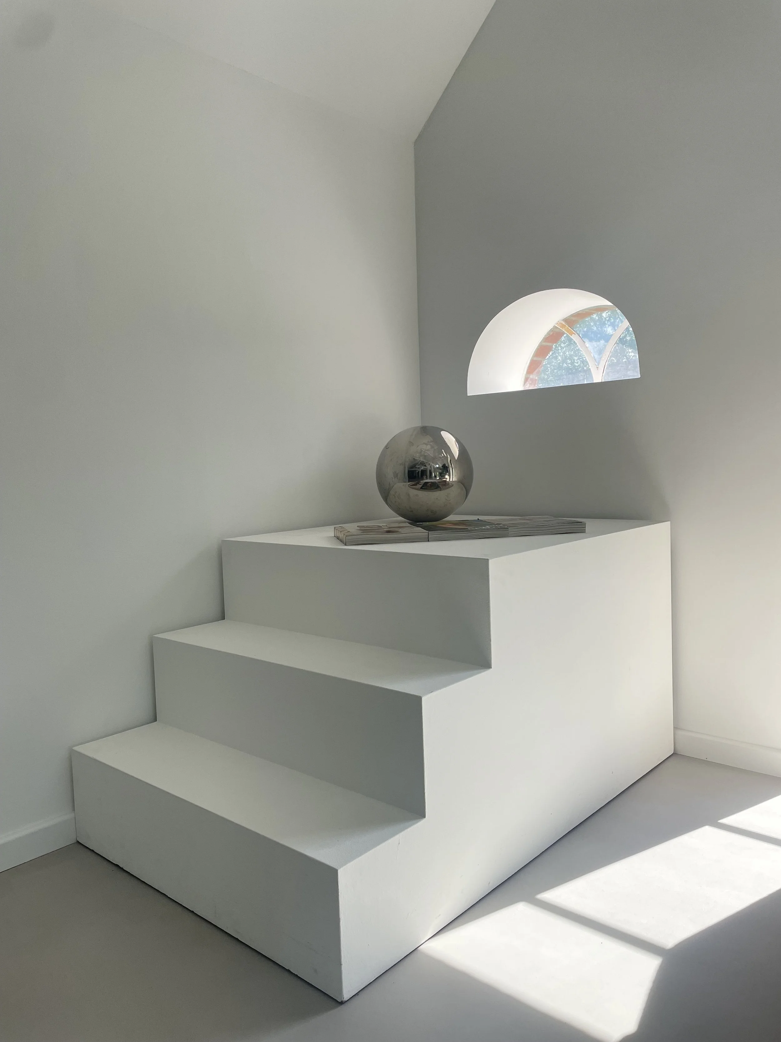 Weißes Podest mit Treppe und rundem Fenster als variables Set für Fotoproduktionen