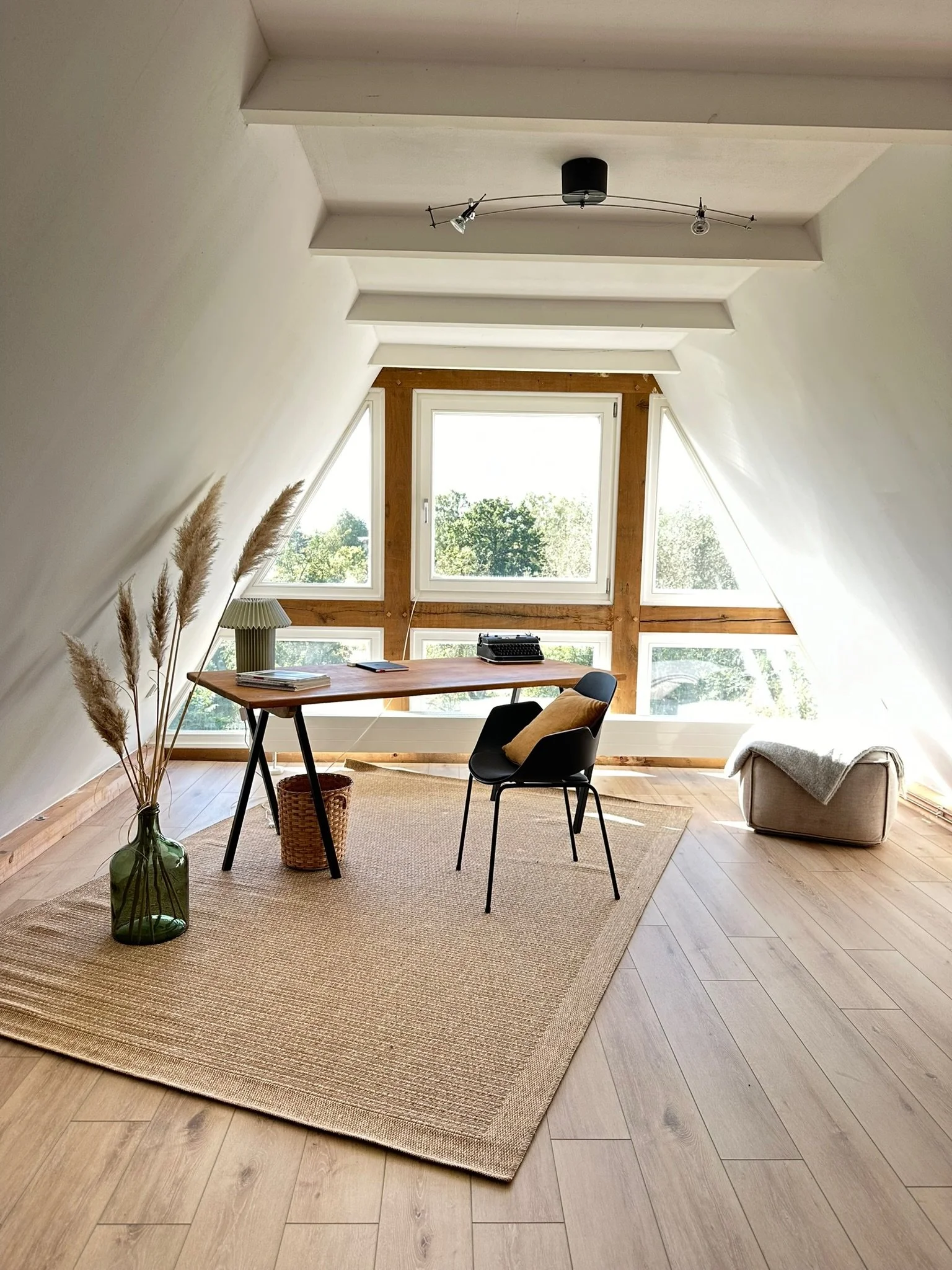 Heller Arbeitsbereich unter dem Dach mit Schreibtisch und Blick in die Natur