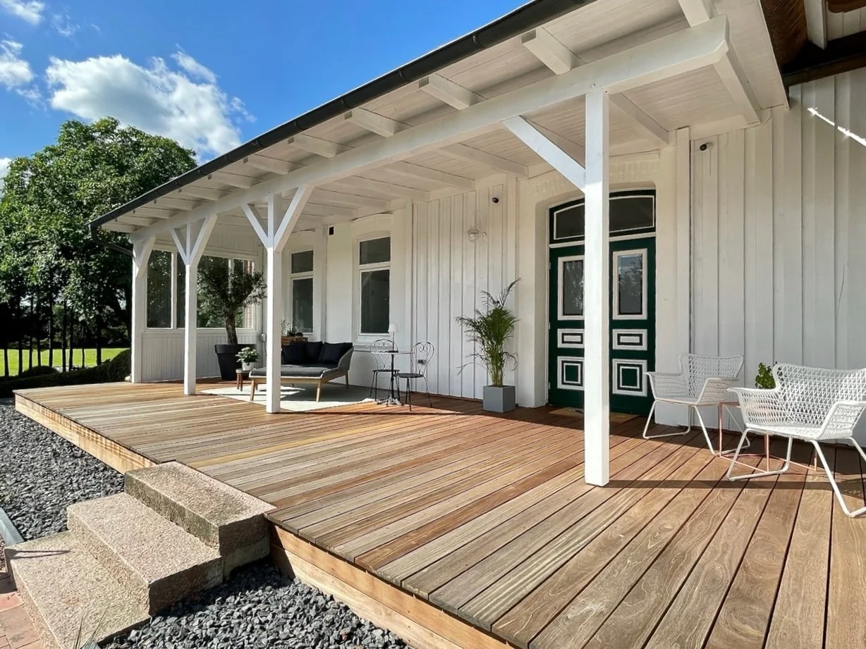 Überdachte Holzterrasse des modernen Bauernhauses mit Blick in den Garten