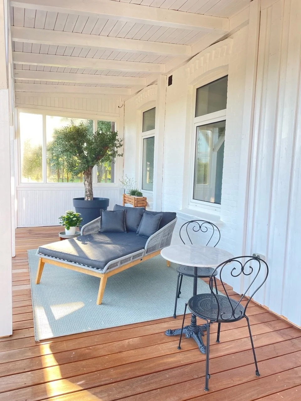 Überdachte Terrasse mit Lounge-Bereich, großem Olivenbaum und Blick in den Garten