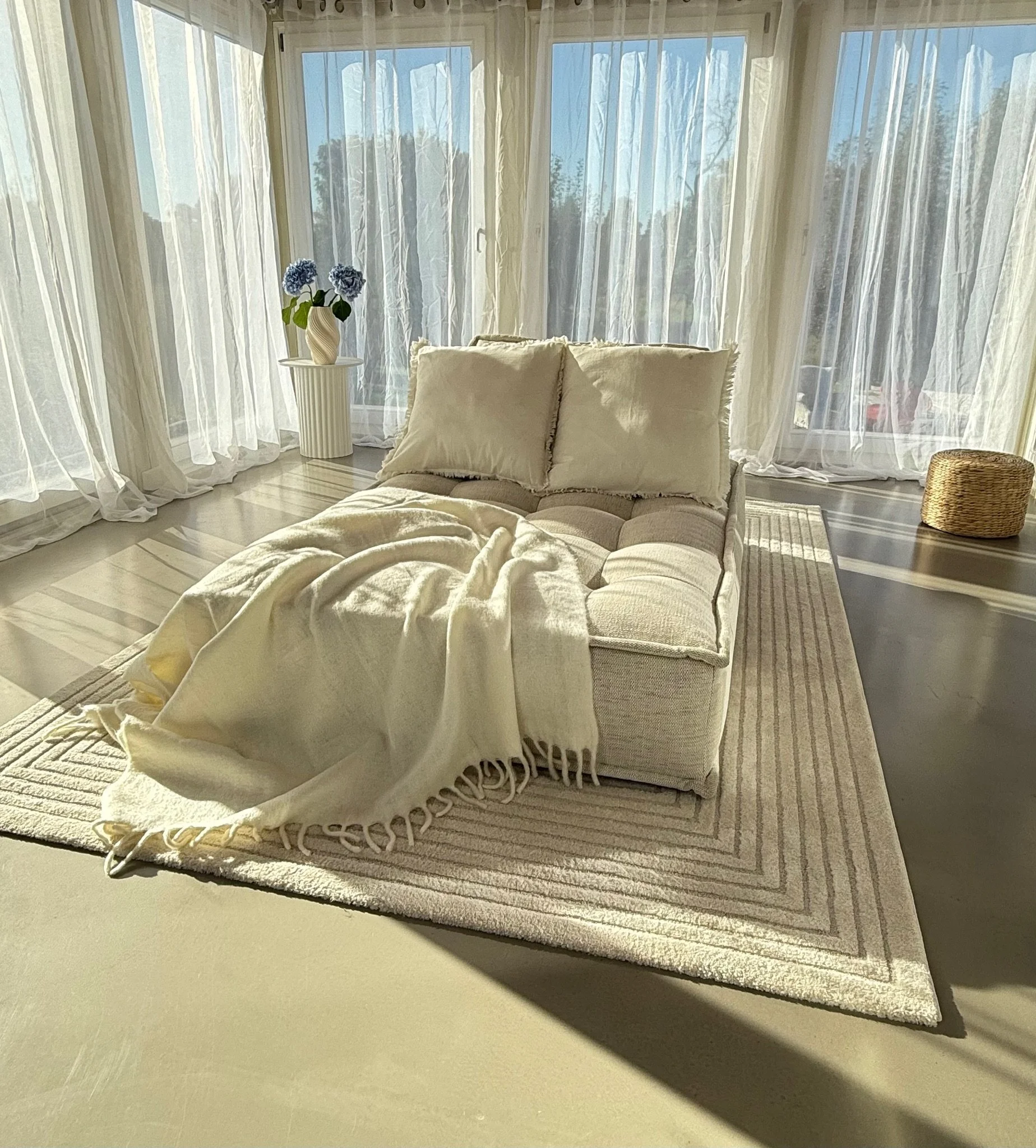 Wohnliches Sofa-Setting im Wintergarten mit weichen Textilien, Vorhängen und natürlichem Tageslicht