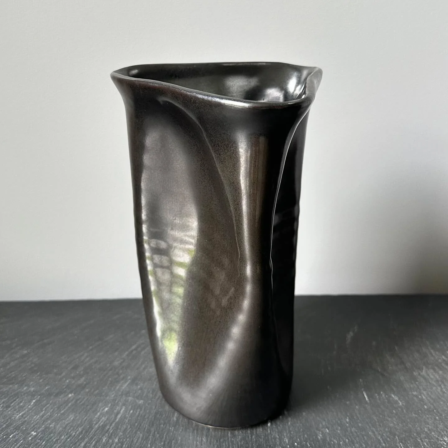 New glaze, new form. This is the first vase I threw, then modified with my fingers into a triangular shape. This new black glaze @powerhouse_arts has an amazing metallic sheen. I love the way my throwing lines are highlighted&mdash;giving it a ribbed