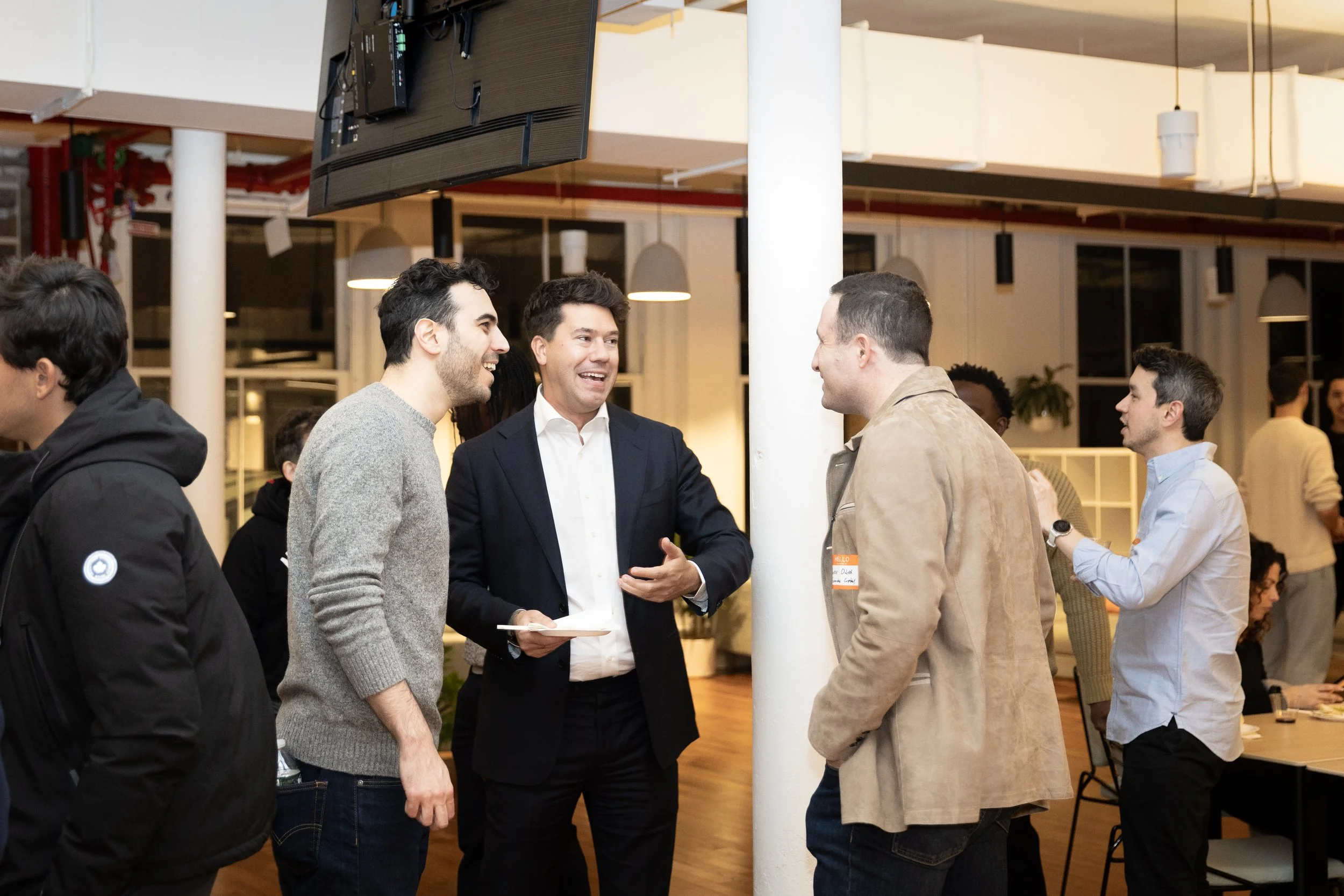 Group of five men engaging in conversation at an indoor social event or networking gathering.