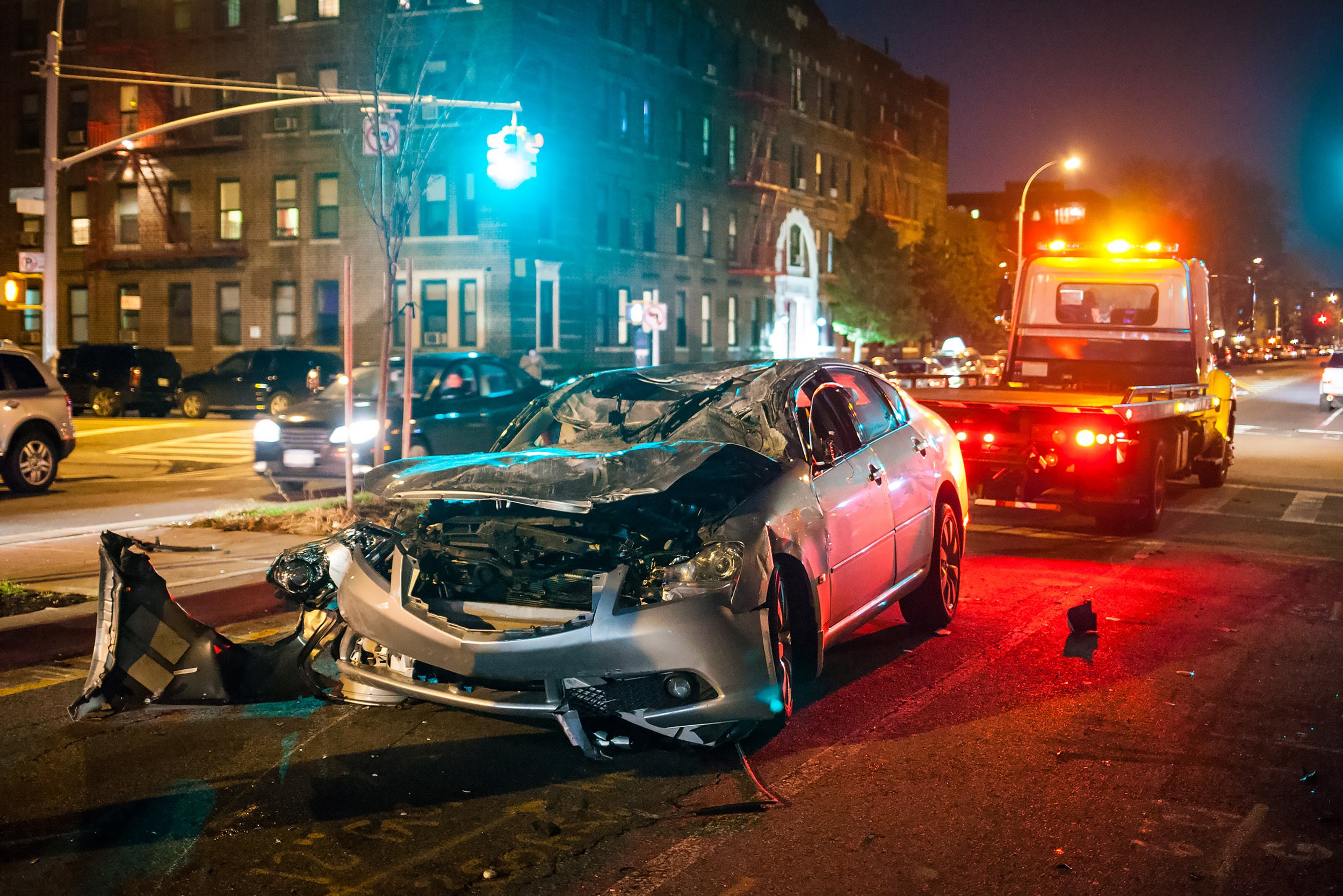 Silver car that has been in a car accident with a tow truck