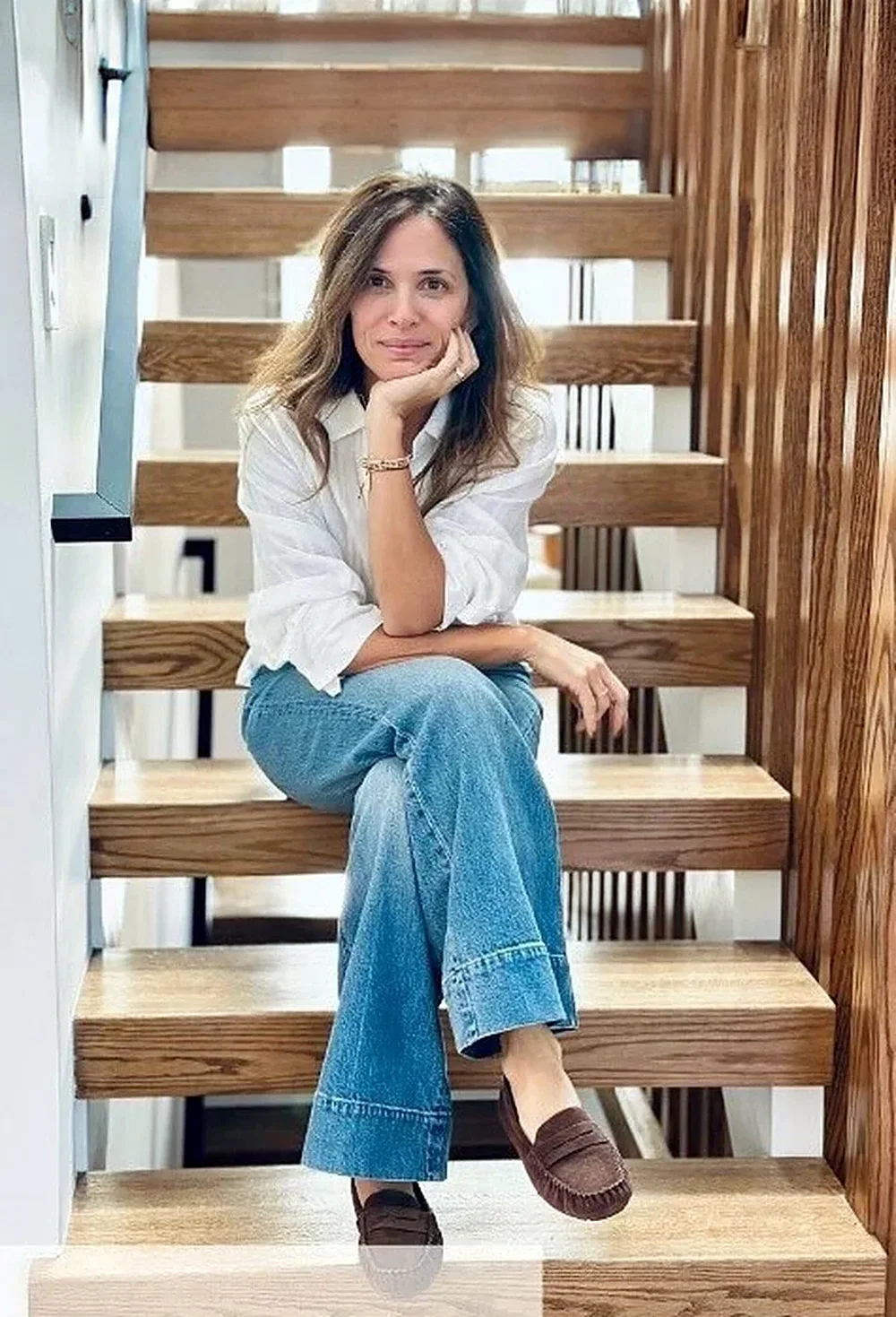 Natalia, interior designer and real estate agent, sitting on an oak staircase