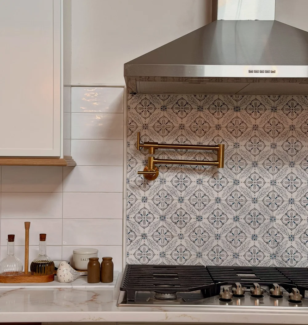 Finished range wall with hand-painted tile and a brass pot filler