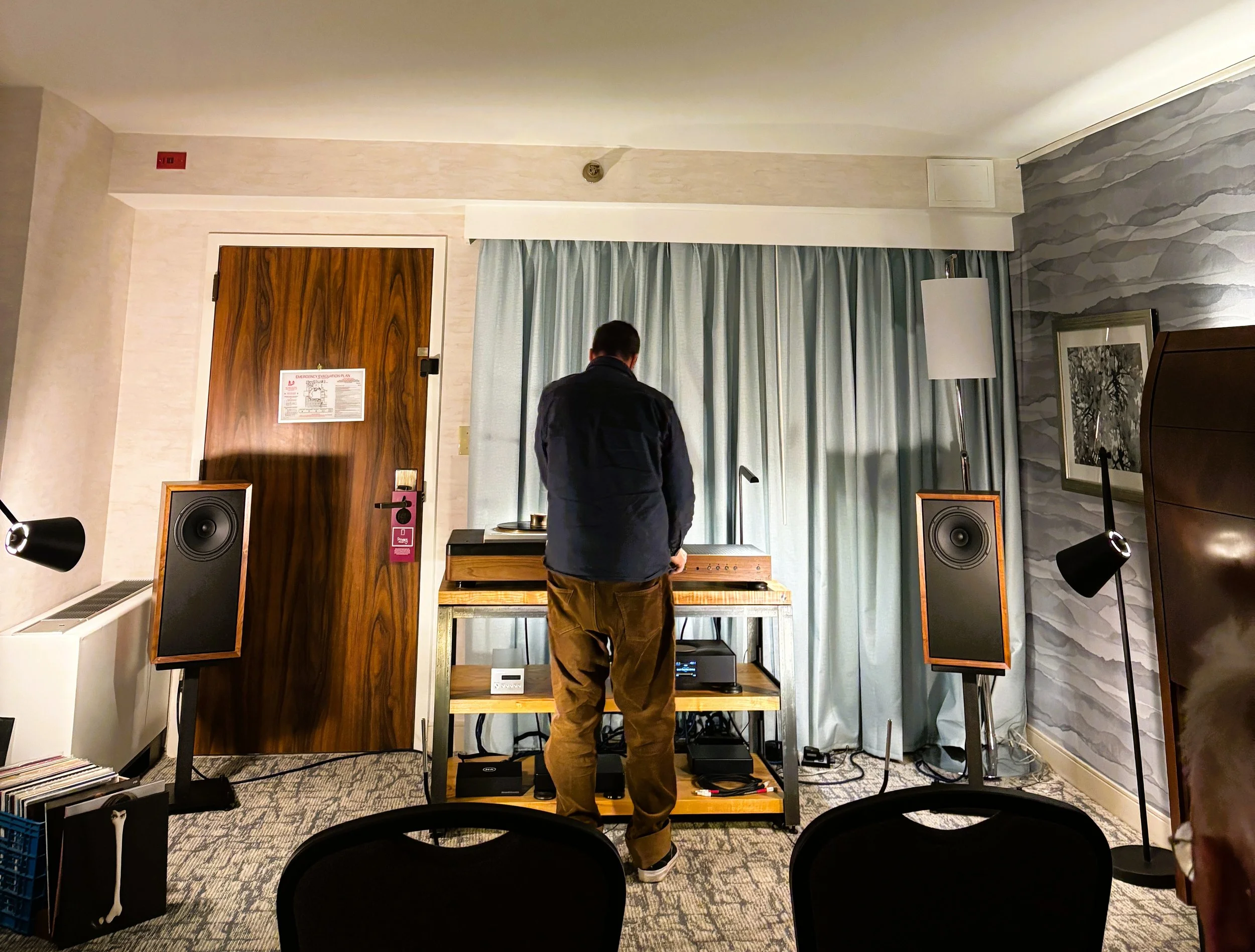 Christopher Hildebrand setting up a Fern & Roby hi-fi system at an audio show in a hotel room, with Raven II speakers and the Archival Turntable