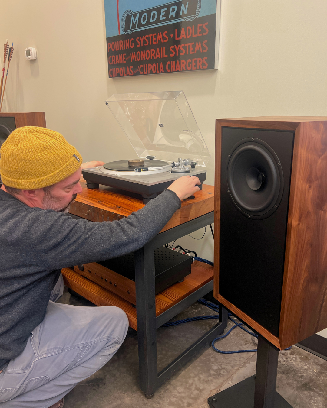 Christopher Hildebrand of Fern & Roby adjusting the office system - Technics SL-1500C, Raven II bookshelf speakers on stands, and a Fern & Roby equipment rack.
