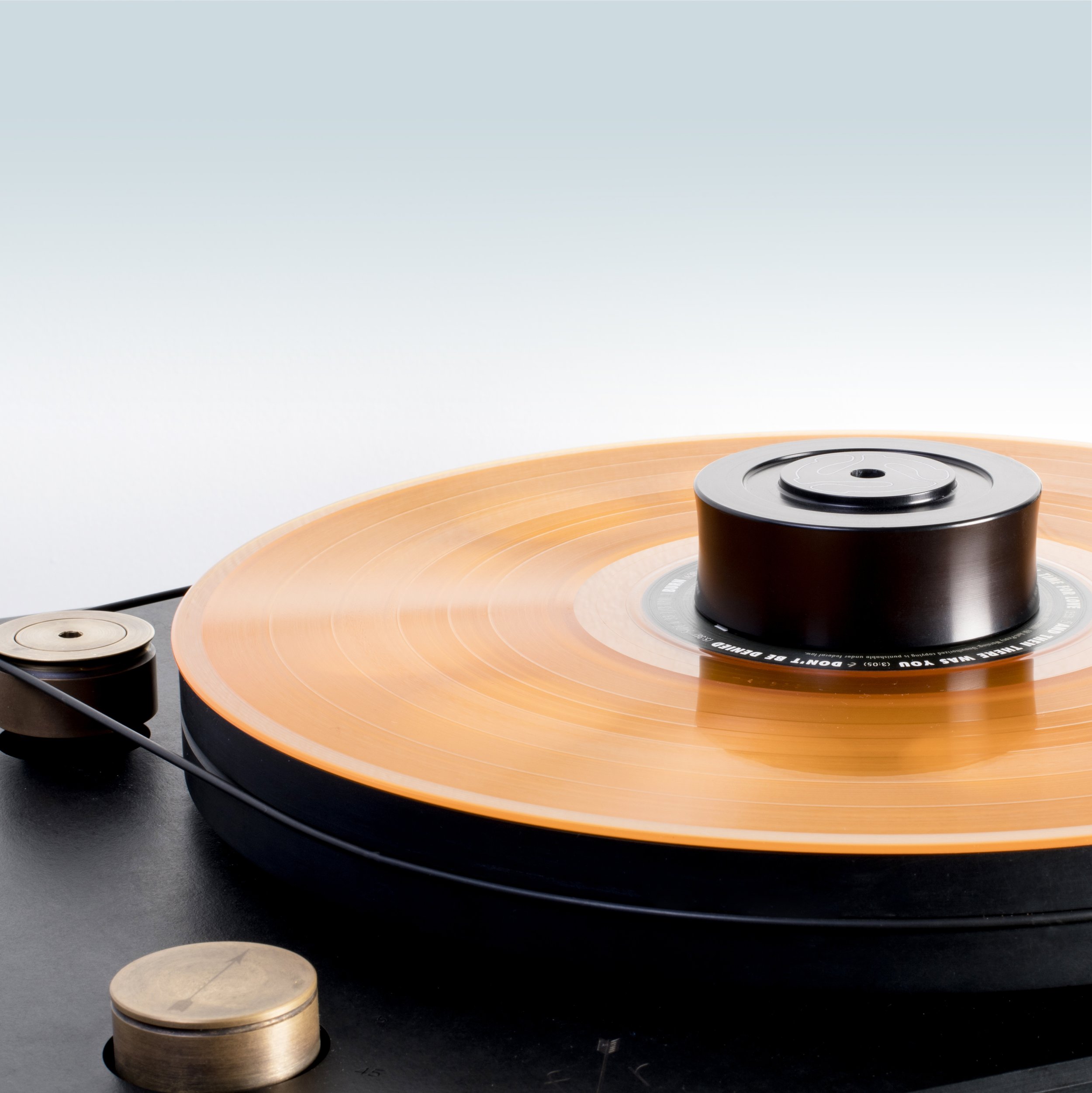 Anodized Aluminum record weight on a belt driven turntable spinning an orange record
