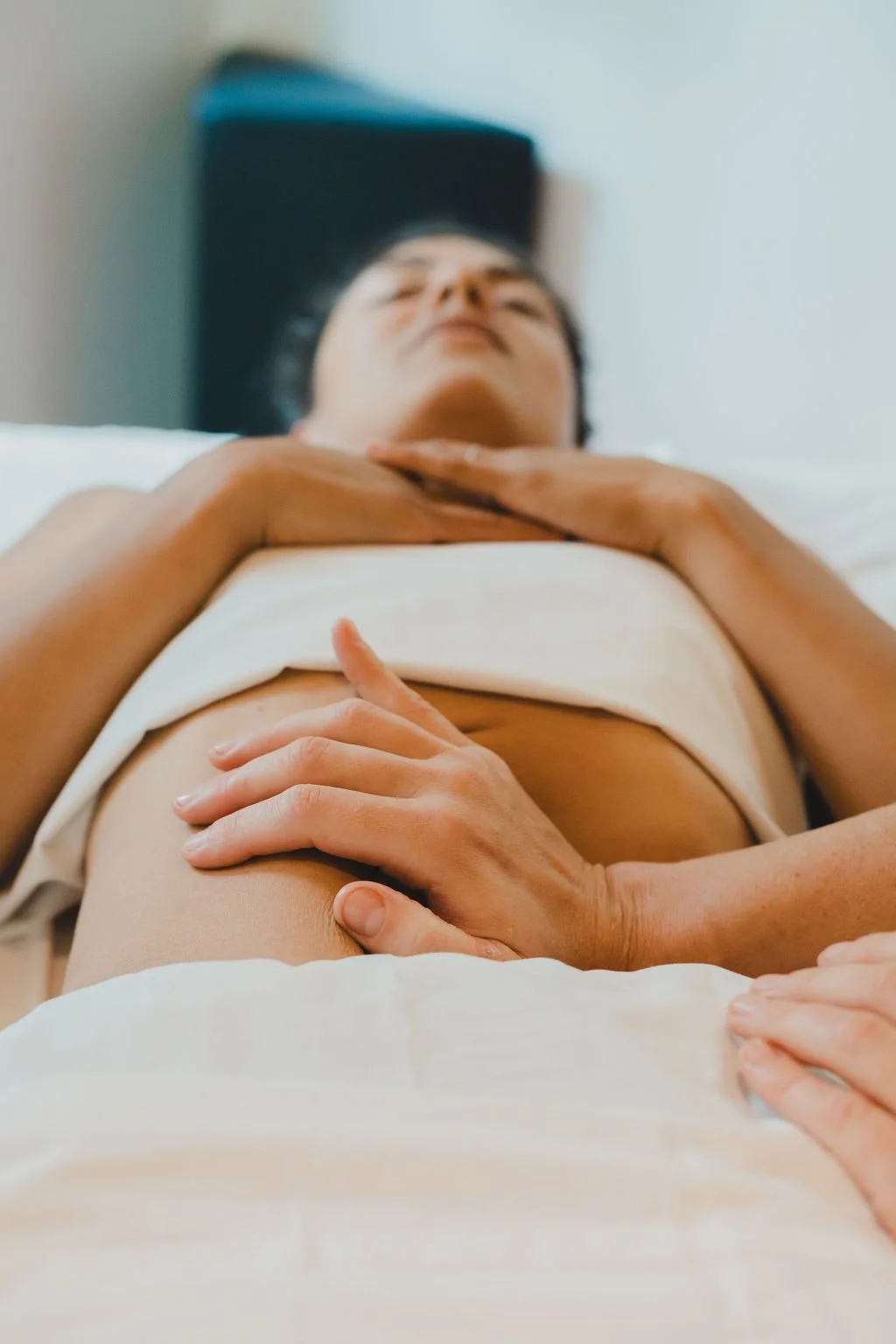Close-up of a person's belly with a cone-shaped moxabustion on top of sliced ginger, with acupuncture needles inserted into the abdomen. 
