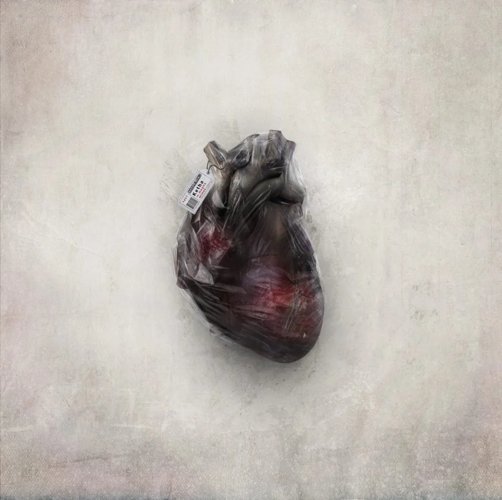 A plastic-wrapped, raw human heart with a barcode tag on a plain, light-colored surface.