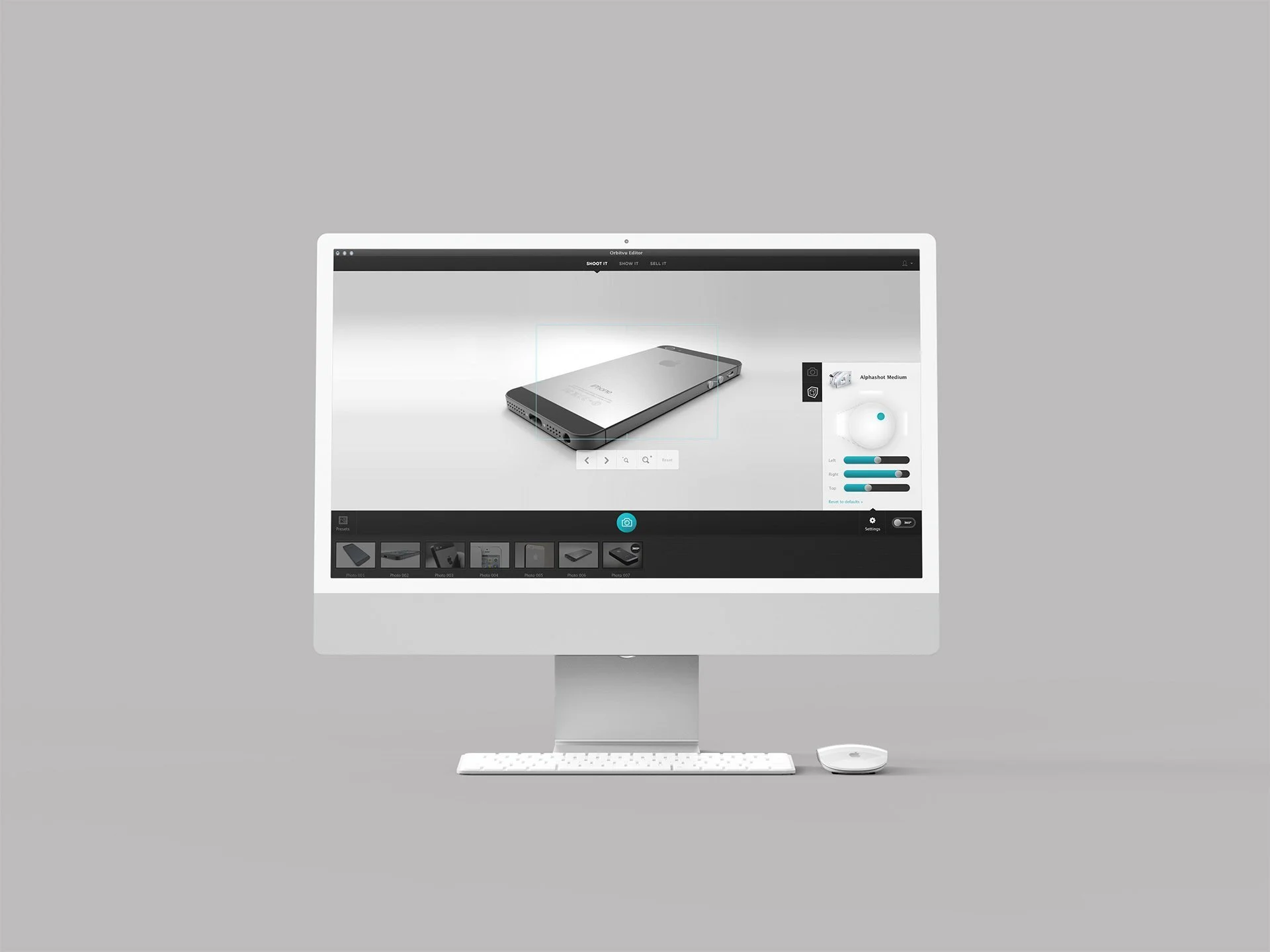 An iMac on a white desk with a white keyboard and mouse, displaying a 3D modeling or photo editing software with a smartphone model on the screen, set against a light gray background.