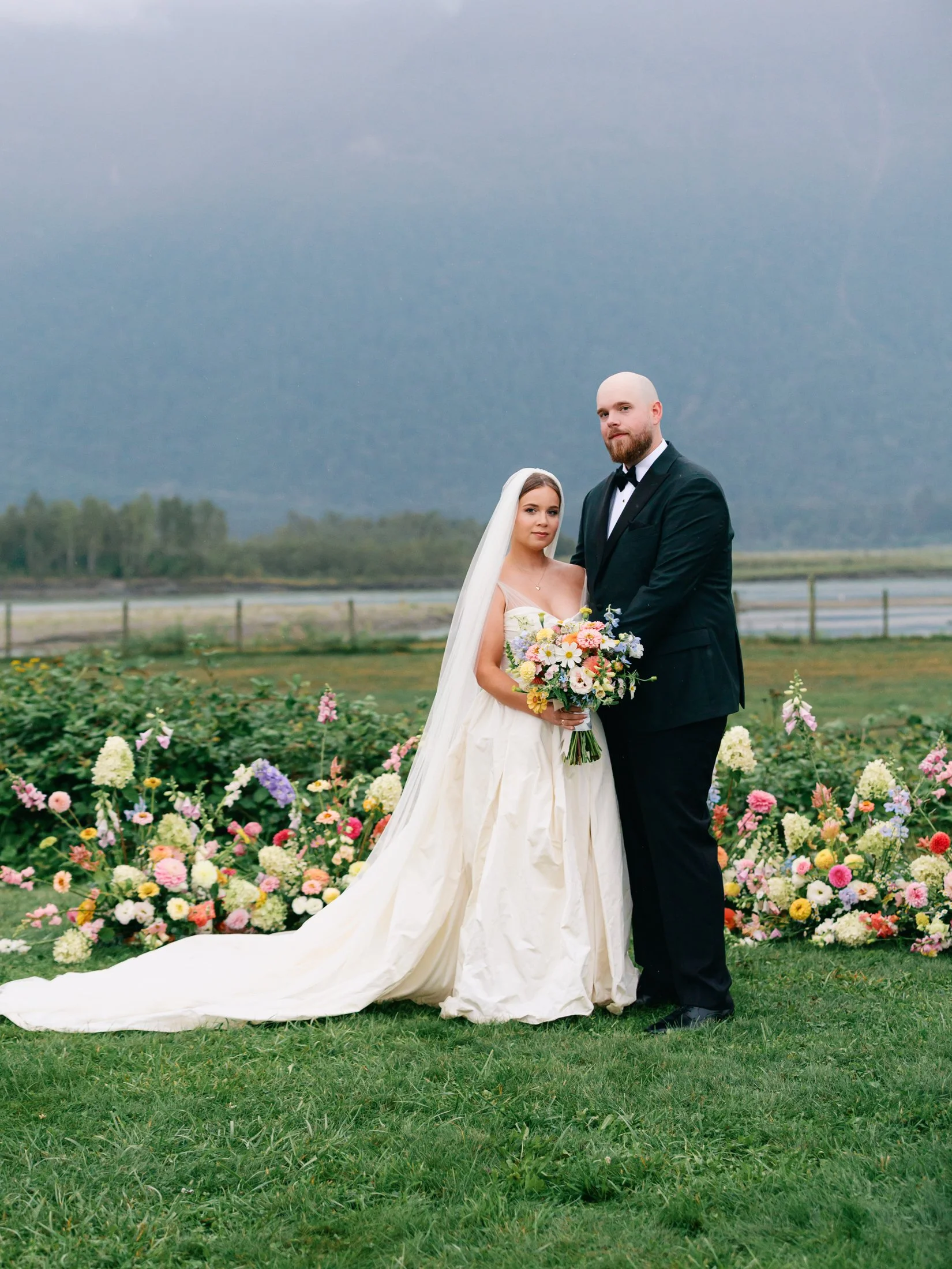 Outdoor editorial portraits at Fraser River Lodge framed by ceremony florals and the mountains, photographed by a Vancouver wedding photographer using film + digital.