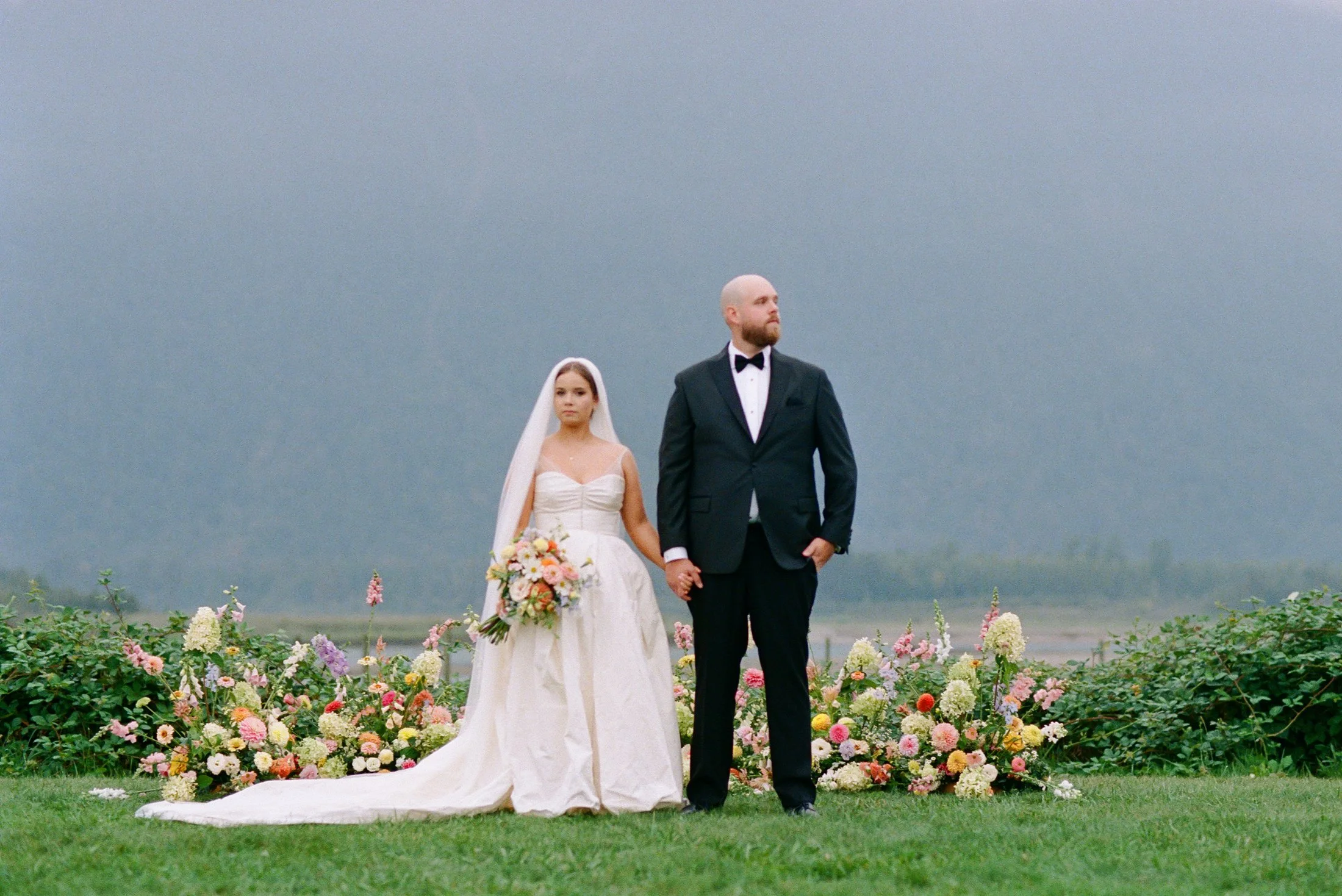 Romantic editorial couple portraits at Fraser River Lodge beside the outdoor ceremony florals, captured in a timeless hybrid film and digital style.
